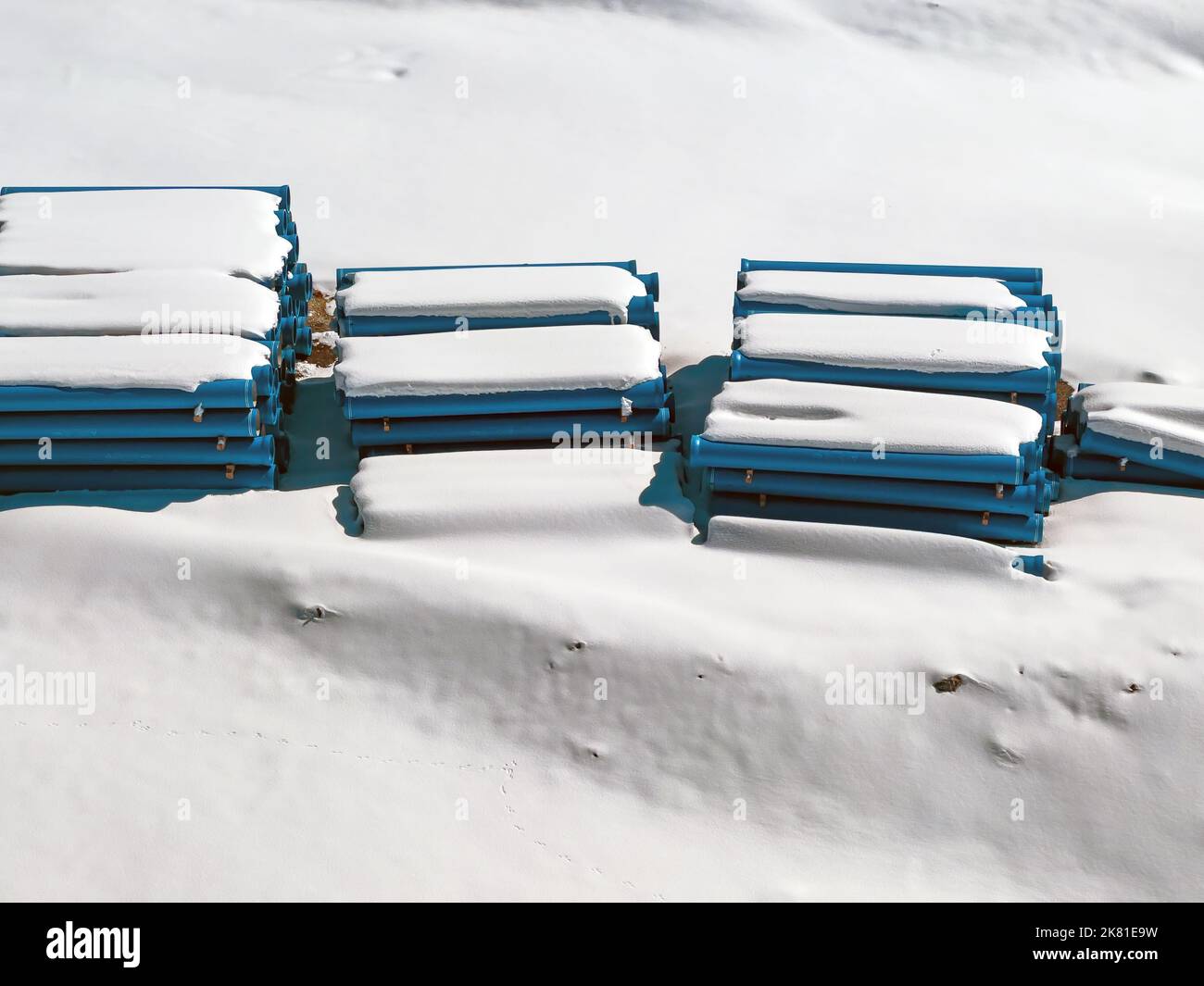 Vista aerea dei tubi di scarico in plastica accatastati nel campo e ricoperti di neve in inverno Foto Stock
