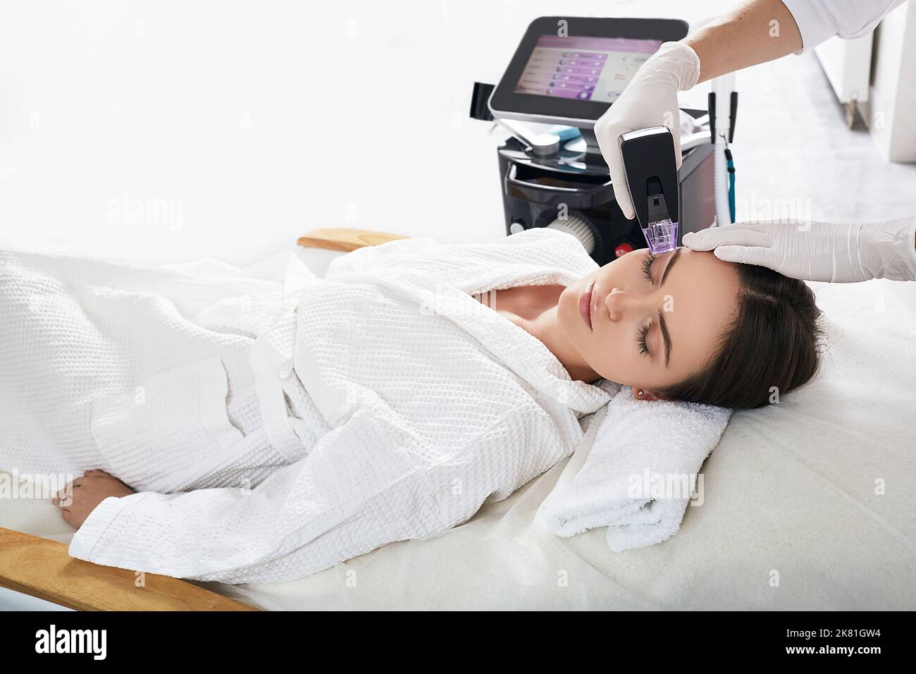 Donna graziosa che gode la procedura di sollevamento di radiofrequenza per il suo ringiovanimento della pelle del viso a cosmetology. Sollevamento RF Foto Stock