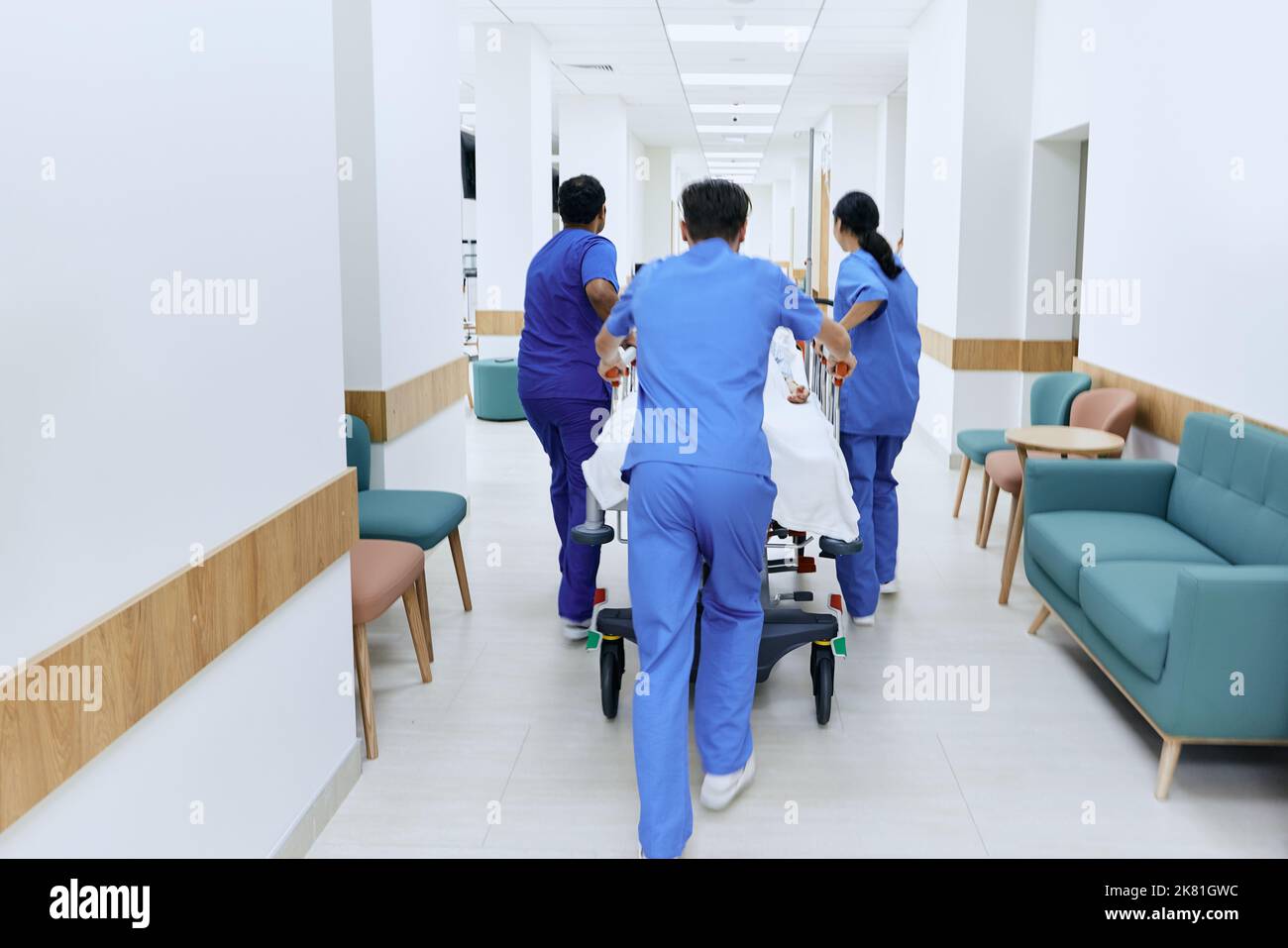 squadra di assistenza ospedaliera che trasportano il paziente sulla barella medica al pronto soccorso dell'ospedale, vista posteriore Foto Stock