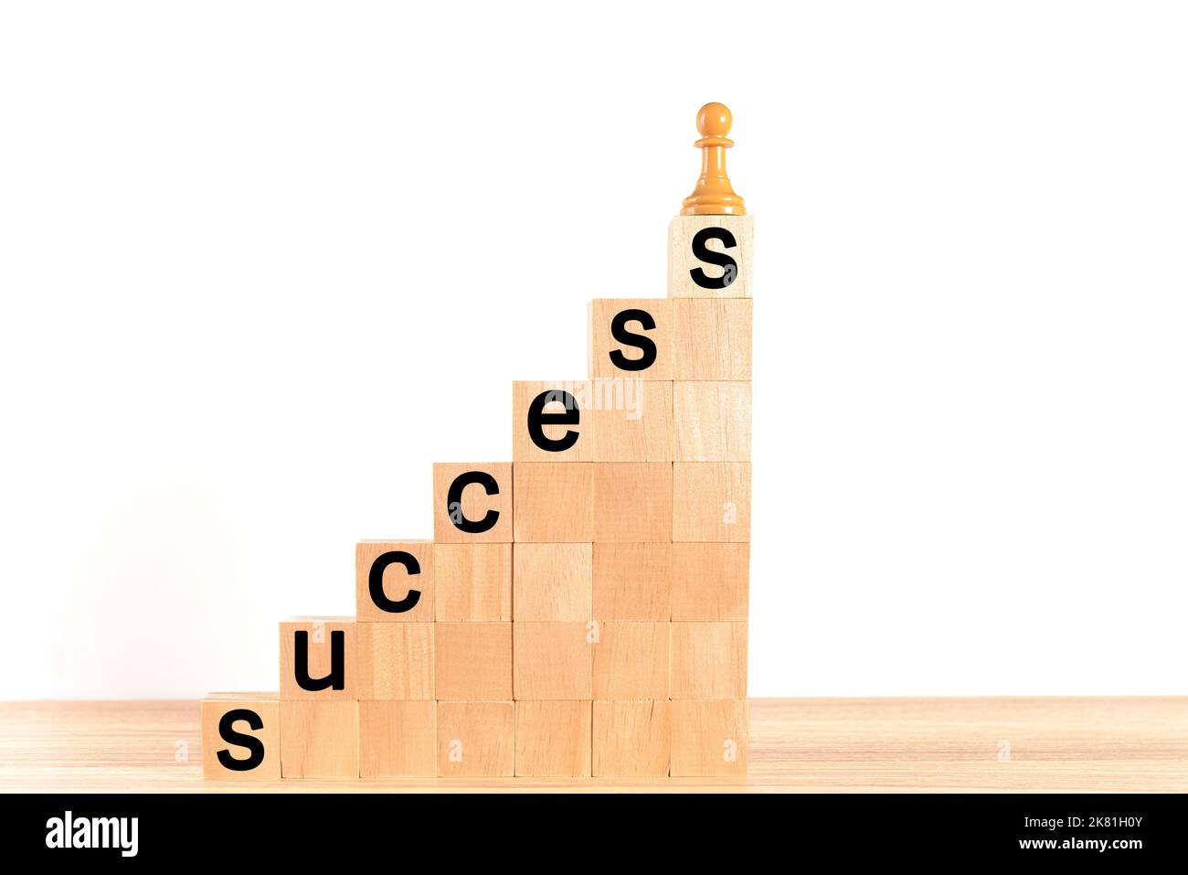 Pedina di scacchi in cima a una scala a blocchi di legno, con la parola 'scess' scritta sui gradini, su sfondo bianco. Concetto di auto-miglioramento, lead Foto Stock