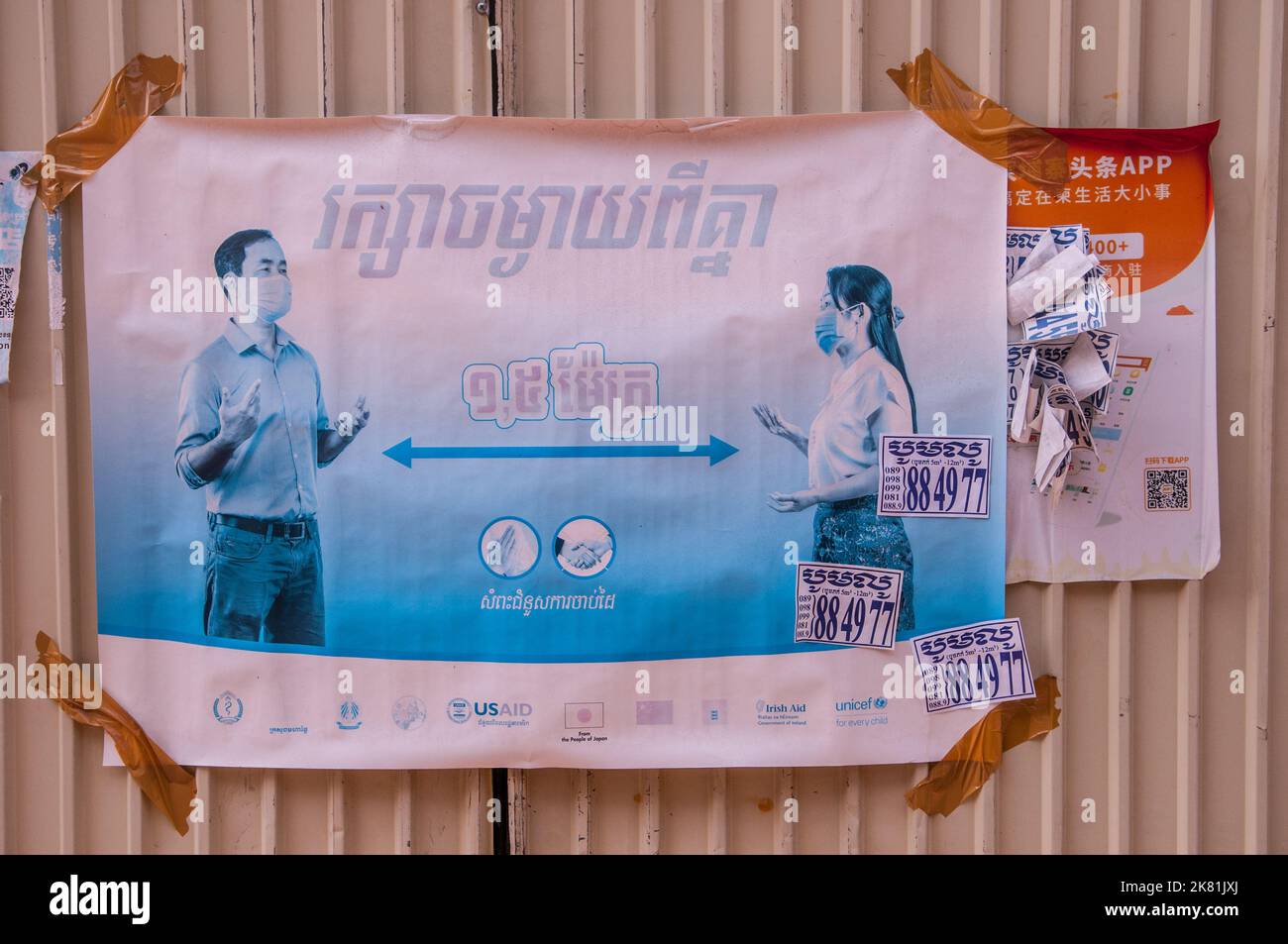 Durante un focolaio di COVID - 19, USAID mette in su manifesti in script Khmer avvertendo i cambogiani circa l'allontanamento sociale. Phnom Penh, Cambogia. © Kraig Lieb Foto Stock