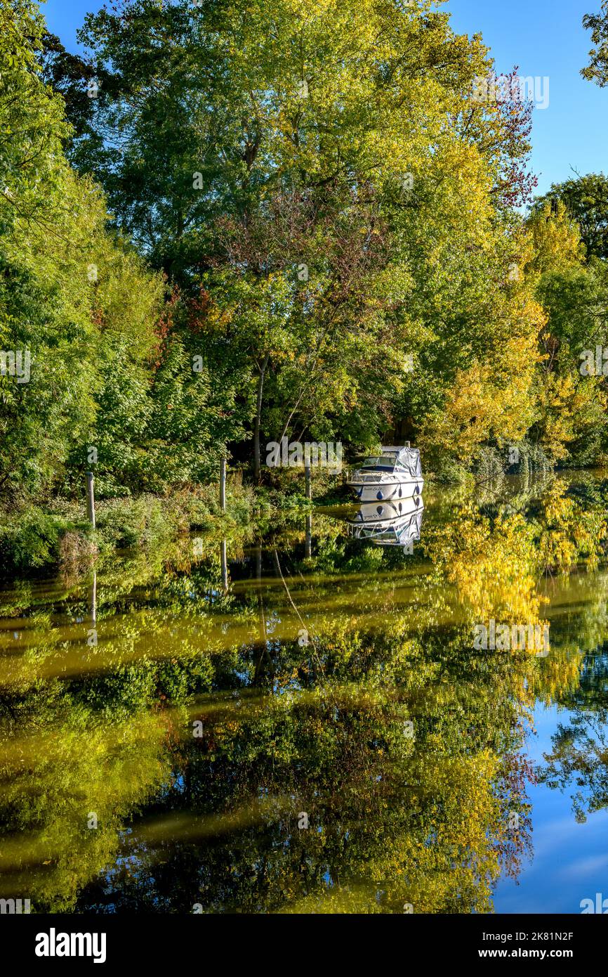 Riflessi autunnali in una curva dolce sul fiume Medway a Tonbridge, Kent, Regno Unito. Un piccolo motoscafo si trova al centro della scena. Foto Stock