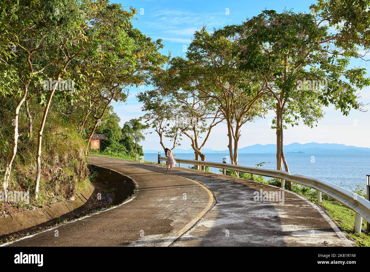 Una donna che cammina sulla strada di cemento al litorale Foto Stock