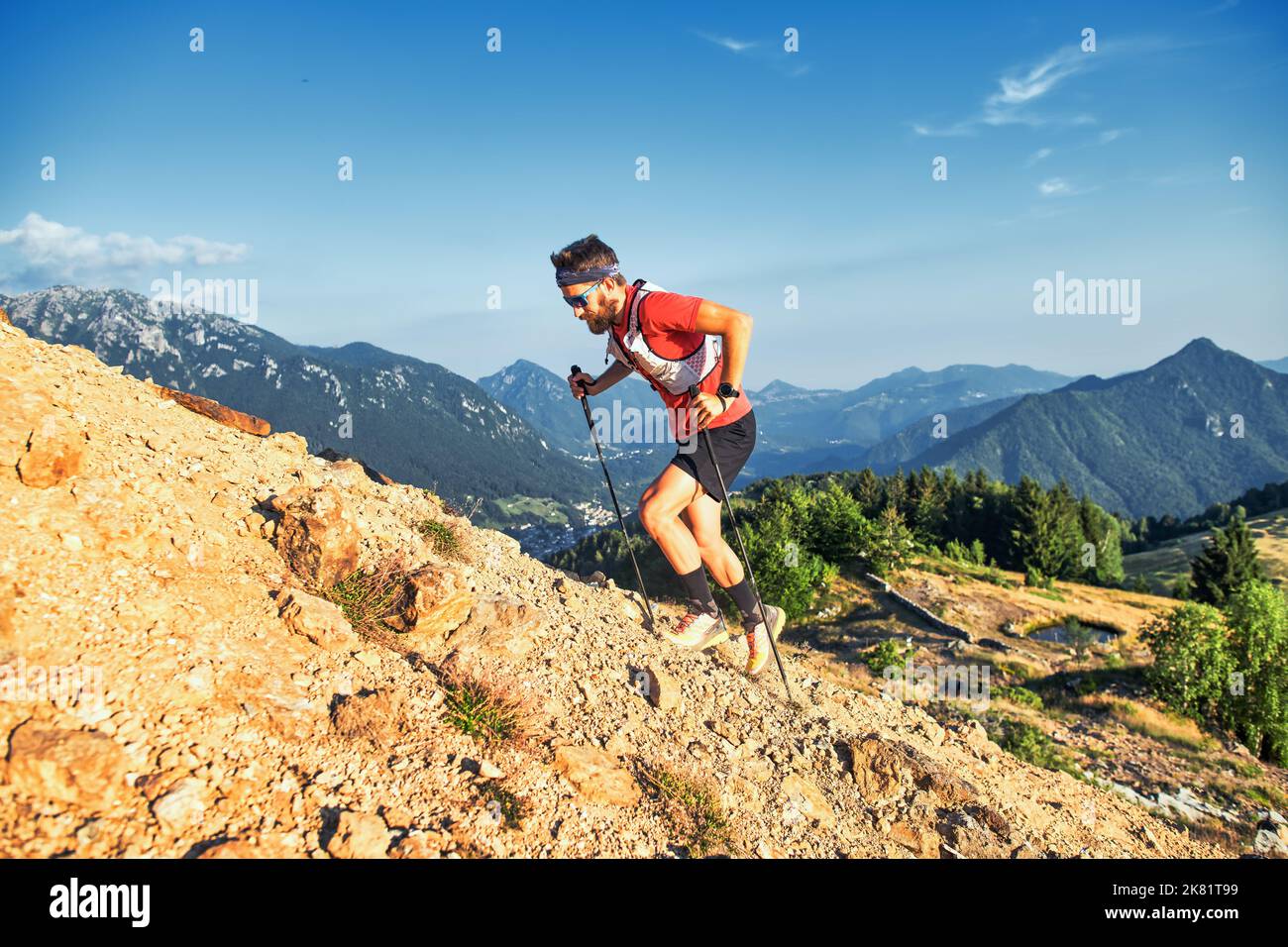 L'uomo sale un pendio roccioso in montagna con pali Foto Stock