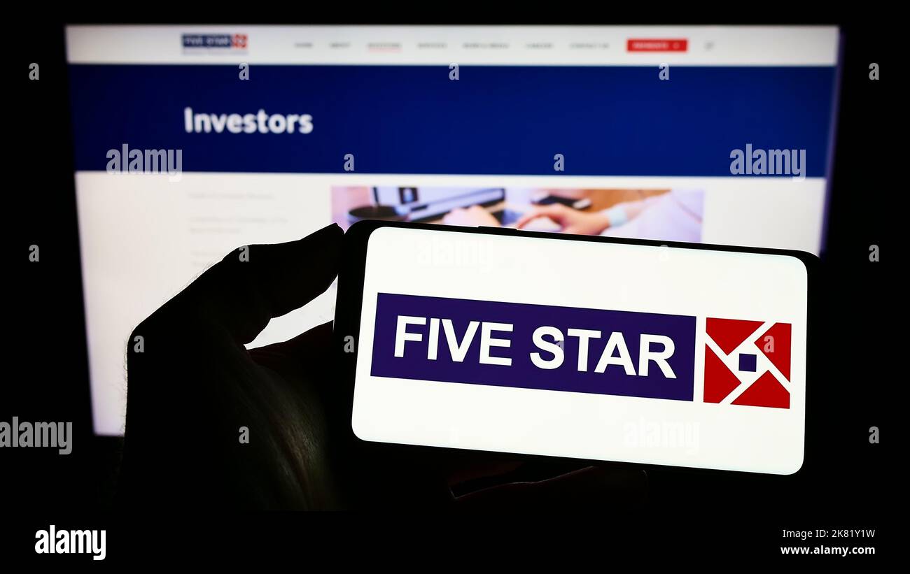 Persona che tiene il cellulare con il logo della società Five-Star Business Finance Limited sullo schermo di fronte al sito web aziendale. Messa a fuoco sul display del telefono. Foto Stock