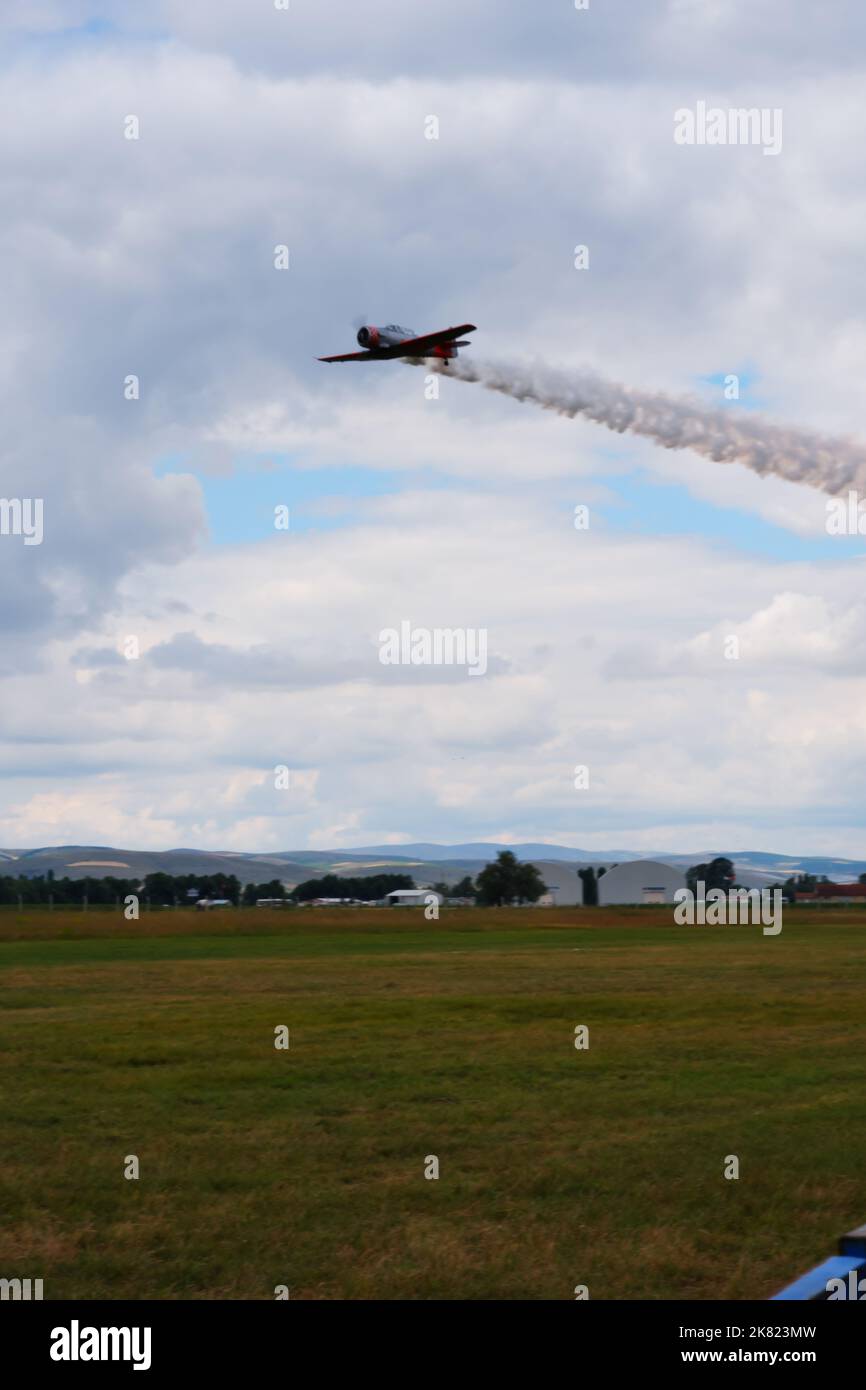 Piccolo aereo che vola vicino a terra con fumo sul retro Foto Stock