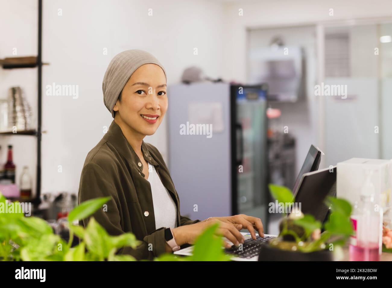 Sicuro proprietario del ristorante donna d'affari in piedi dietro il bancone e utilizzando il portatile mentre lavora. Foto Stock