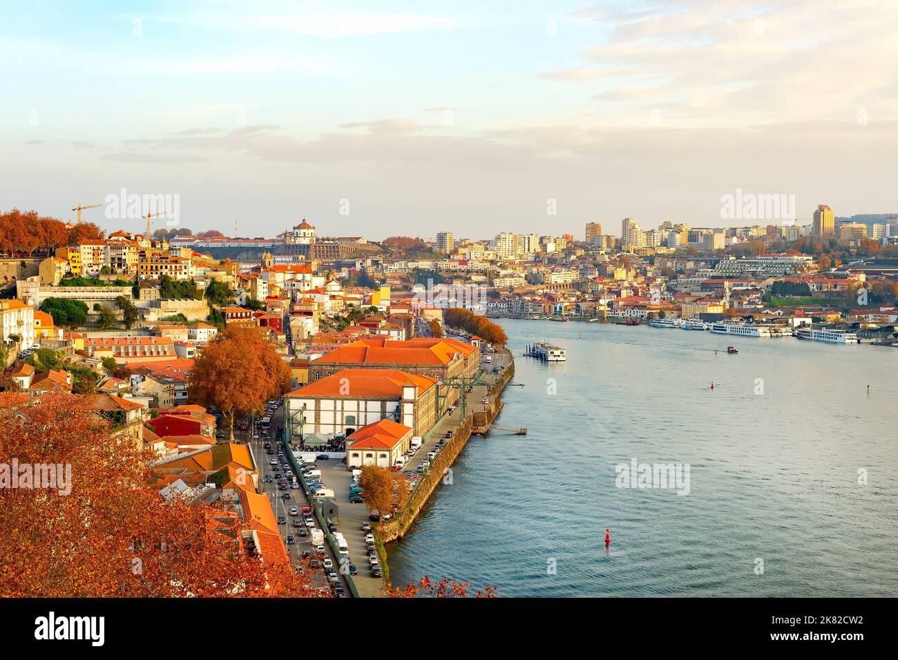 Paesaggio urbano autunnale con il fiume Douro, barche, alberi d'oro, architettura tradizionale, Porto, Portogallo Foto Stock