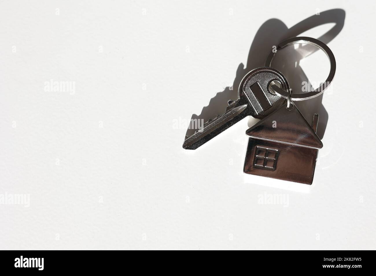 Portachiavi e portachiavi a forma di casa in metallo disposti su sfondo bianco con ombra. Commercio e assicurazione. Concetto di acquisto, vendita, locazione di vera esta Foto Stock