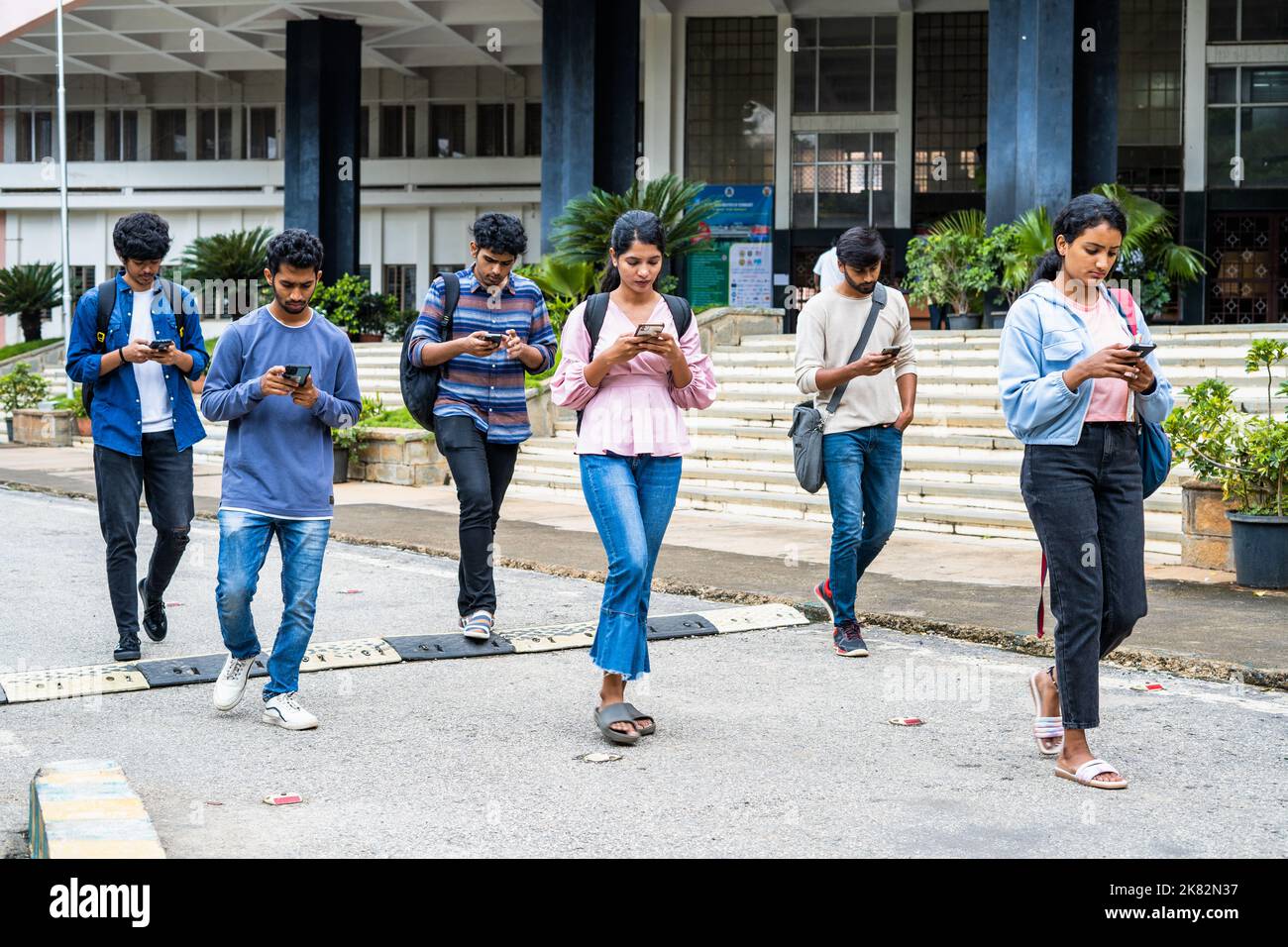 gruppo di studenti impegnati a controllare i risultati o a utilizzare il telefono cellulare presso il campus universitario - concetto di social media, dipendenza da smartphone e tecnologia. Foto Stock