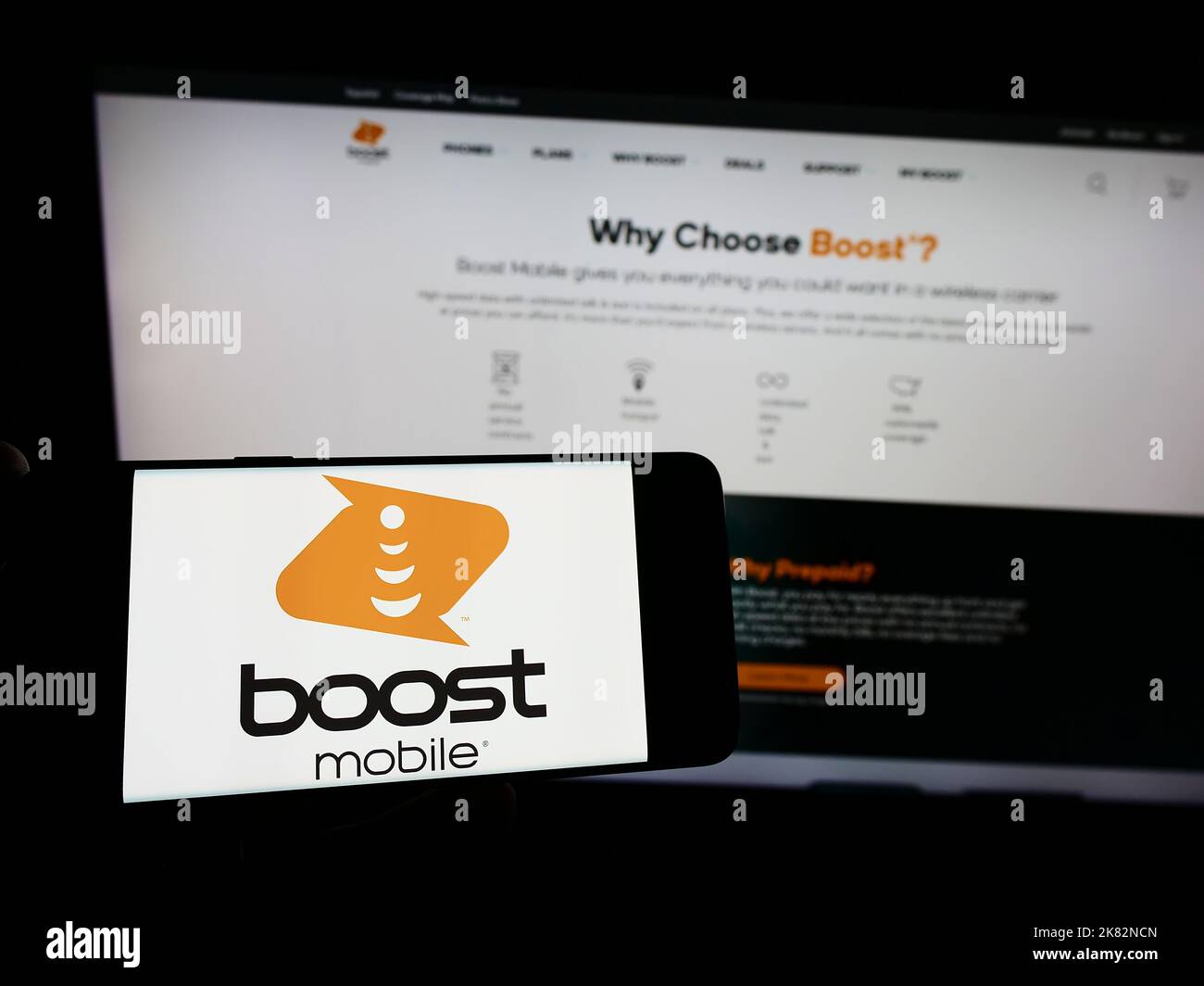 Persona che tiene in mano uno smartphone con il logo della società di telecomunicazioni statunitense Boost Mobile sullo schermo di fronte al sito Web. Messa a fuoco sul display del telefono. Foto Stock