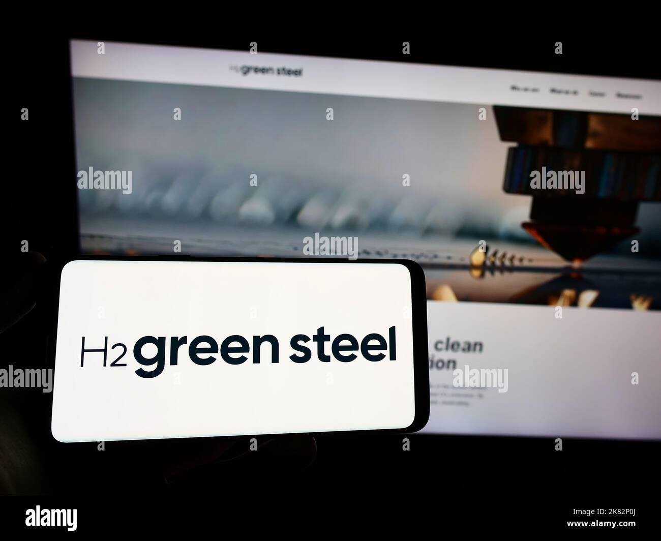 Persona che tiene uno smartphone con il logo della società svedese di idrogeno H2 Green Steel sullo schermo di fronte al sito Web. Messa a fuoco sul display del telefono. Foto Stock