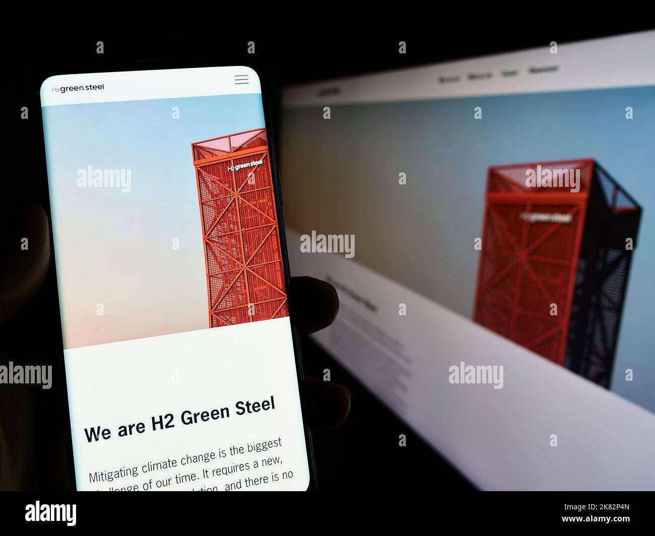 Persona che tiene il cellulare con pagina web della società svedese di idrogeno H2 Green Steel sullo schermo di fronte al logo. Messa a fuoco al centro del display del telefono. Foto Stock