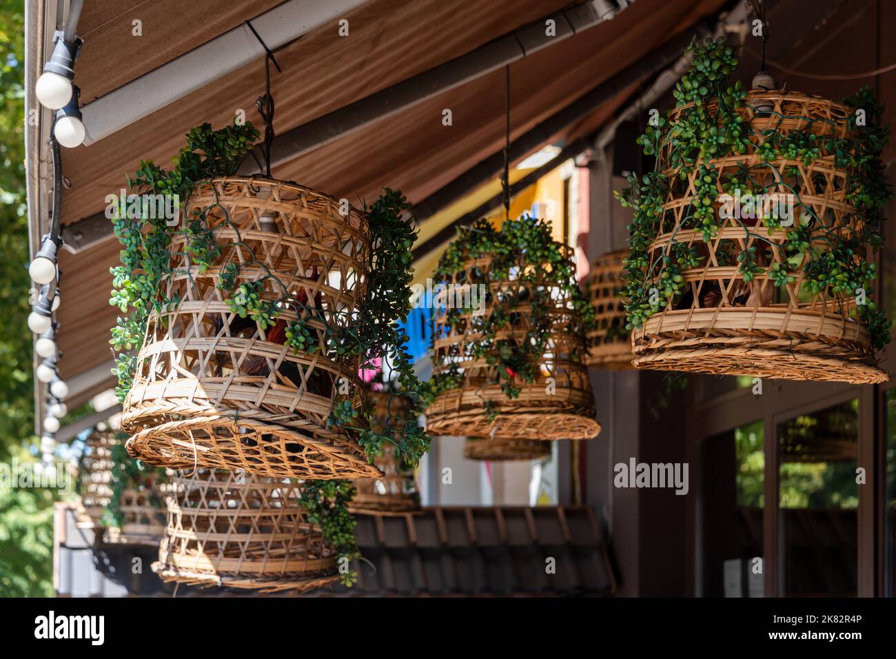 Paralumi in vimini in un bar all'aperto. Decorazioni di lampade a lanterna appese in vimini di legno in bambù. Decorazioni vintage del ristorante asiatico. Foto Stock