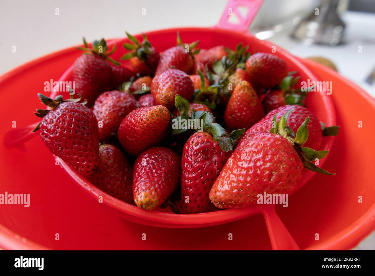 utensile da cucina, fragole fresche lavate in un filtro, frutta deliziosa, ingrediente per la cottura, la vita domestica Foto Stock