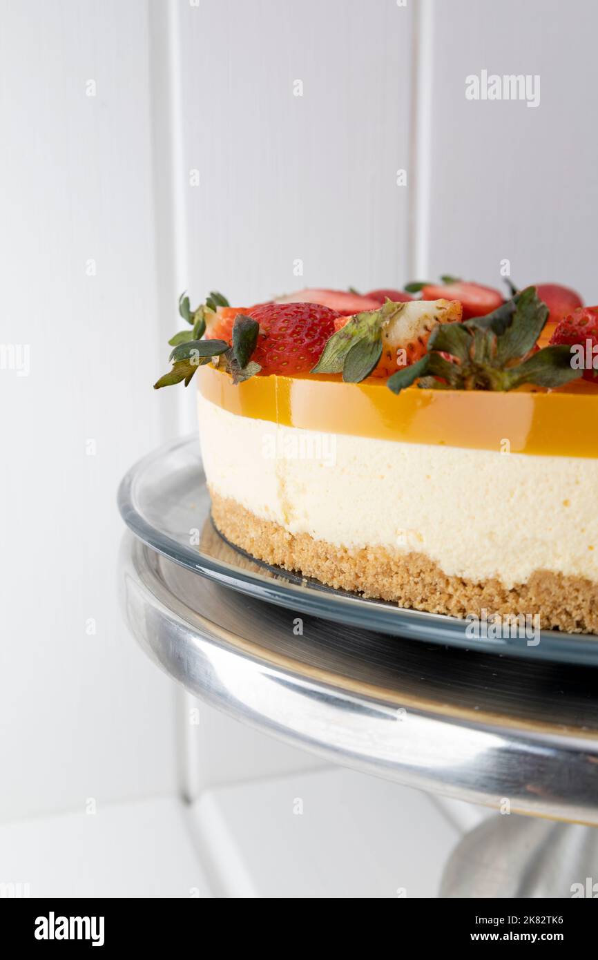 approccio alla cheesecake frutto della passione, pasticceria con deliziosi dessert decorati con fragole fresche, cibi dolci Foto Stock