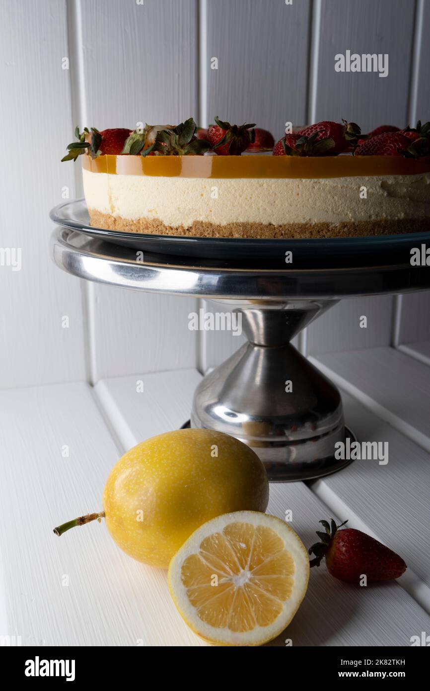tavolo con una cheesecake alla frutta della passione, pasticceria con frutta deliziosa, dolce come delizia, festa Foto Stock