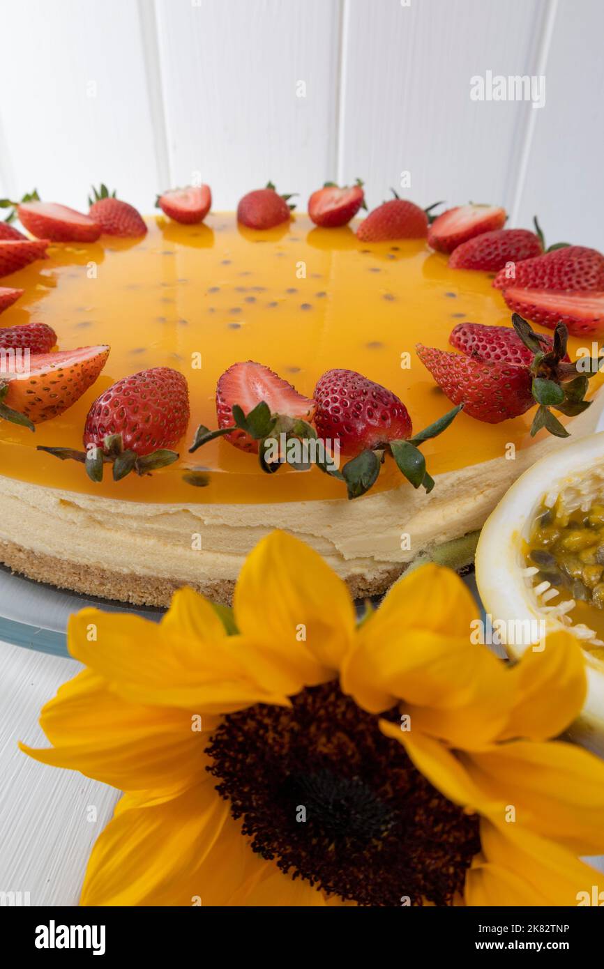 appetitosa carta da parati dolce con crema, gelatina, fiore di fragola e frutto della passione su un tavolo, decorazione pasticceria Foto Stock