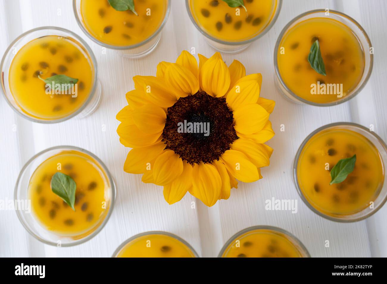 tavolo decorato con un girasole e attorno ad esso bicchieri con dessert di frutta passione, antipasti gourmet in studio, dolci Foto Stock
