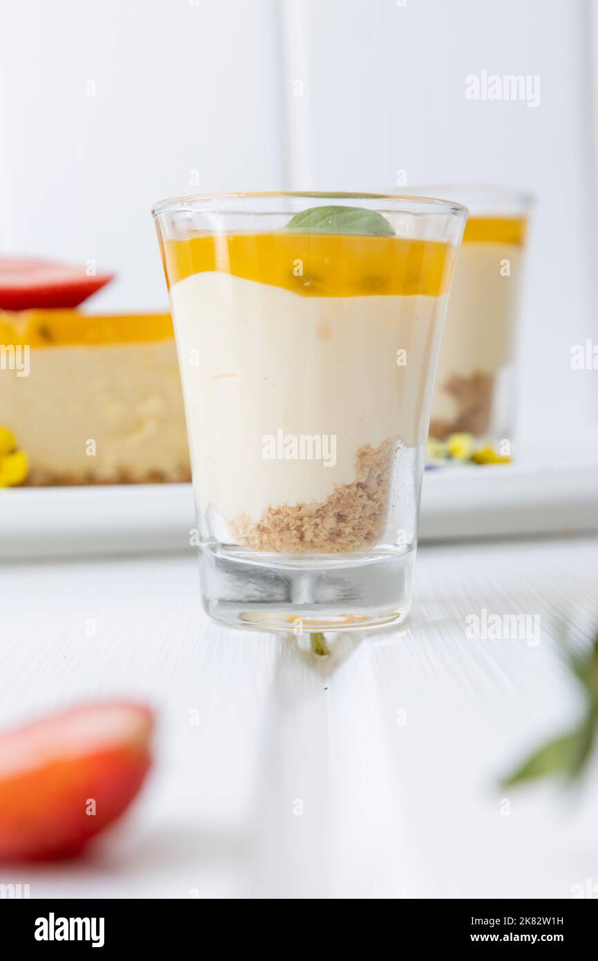 bicchiere con crema e frutta come decorazione accanto a un pezzo di torta, delizioso dolce in studio, pasticceria Foto Stock