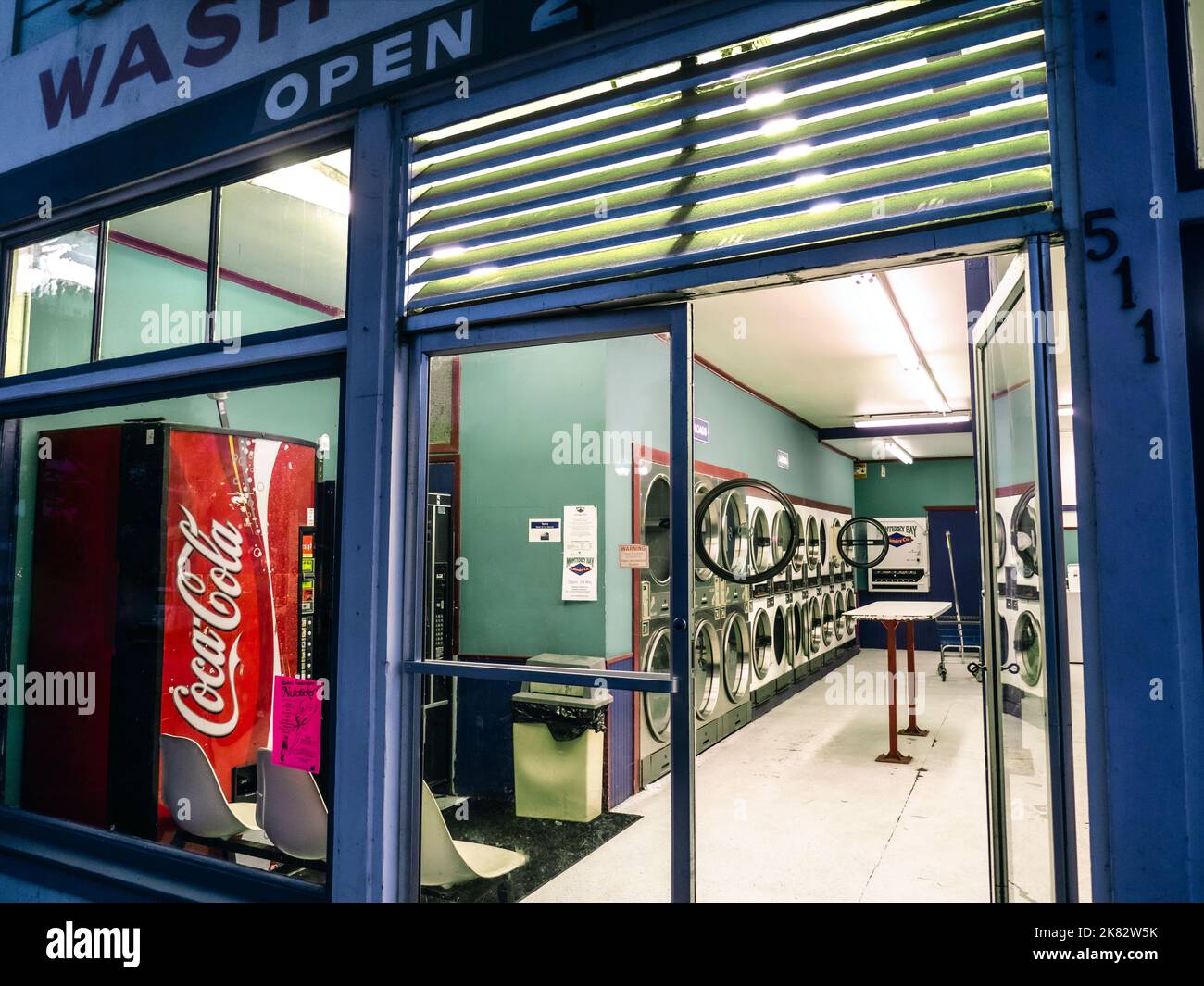 Lavanderia automatica AMERICANA, lavatrice a gettoni, interno con porta della lavatrice aperta e macchina Coca Cola di notte, Pacific Grove California USA lifestyle Foto Stock