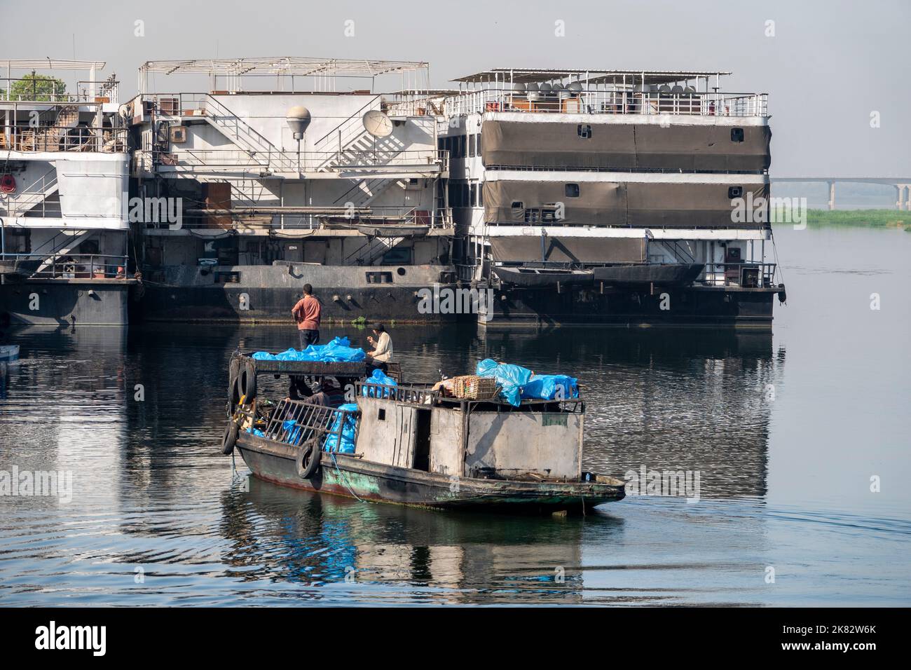 Una chiatta di smaltimento dei rifiuti per le navi da crociera del Nilo che si avvicinano a tre incrociatori ormeggiati Foto Stock