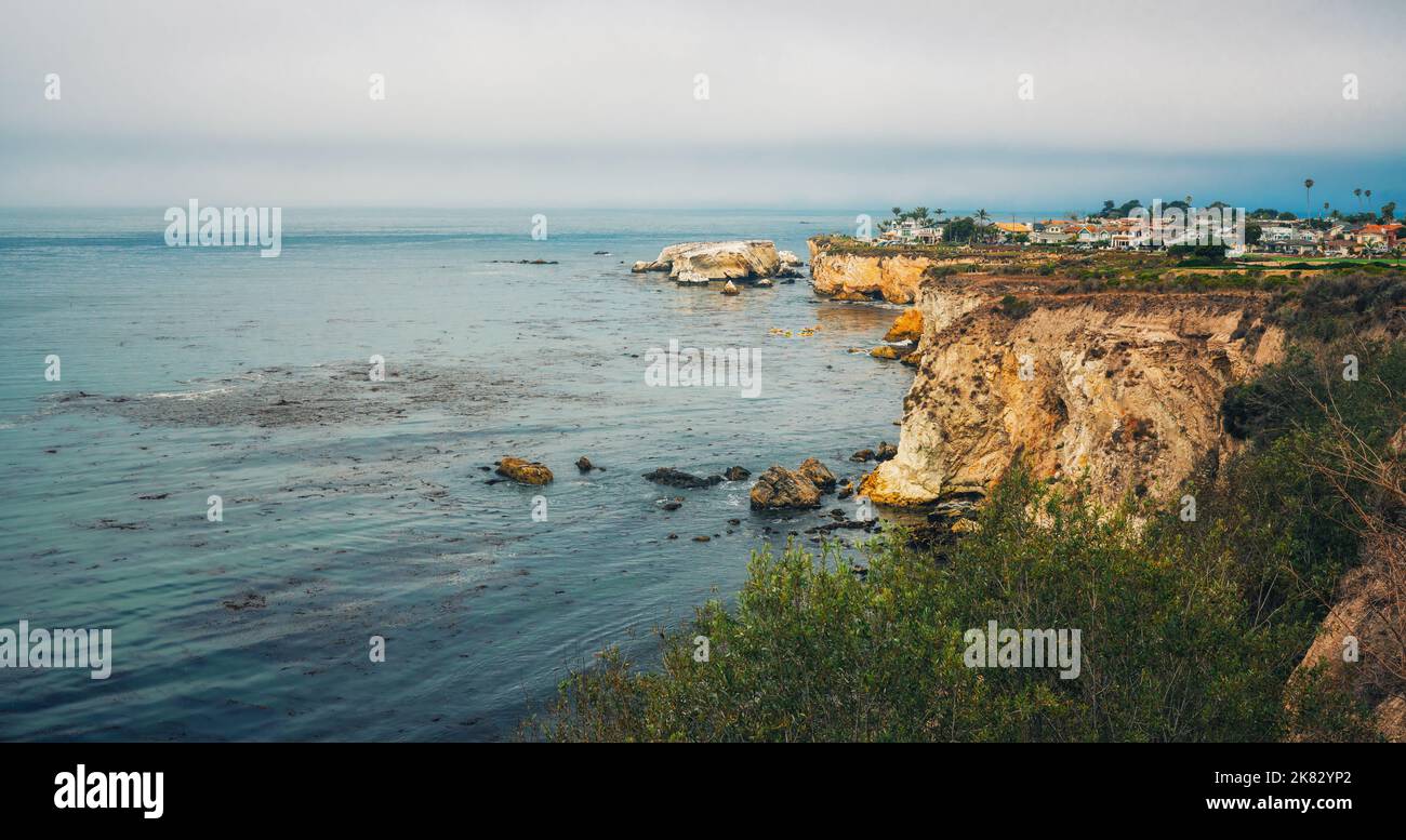 Scogliere rocciose al sole e la silhouette di una bella città sulla spiaggia. Shell Beach a Pismo Beach, California Central Coast Foto Stock