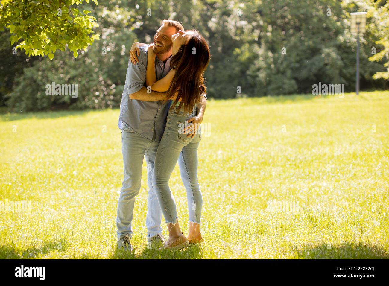 Felice giovane coppia innamorata al campo di erba su una giornata estiva Foto Stock