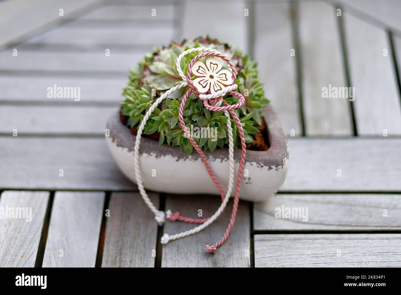 Una ciotola di terracotta a forma di cuore con tessere e nastri decorativi Foto Stock