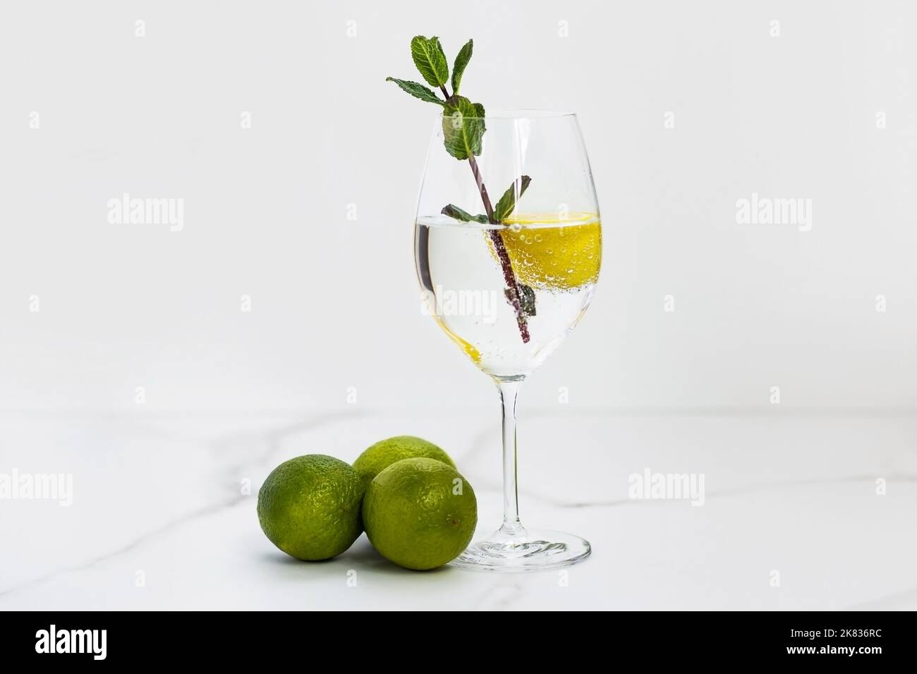 Un bicchiere d'acqua, limone, menta e lime su una tavola bianca per una vita sana, energia, termoregolazione e normalizzazione della digestione Foto Stock