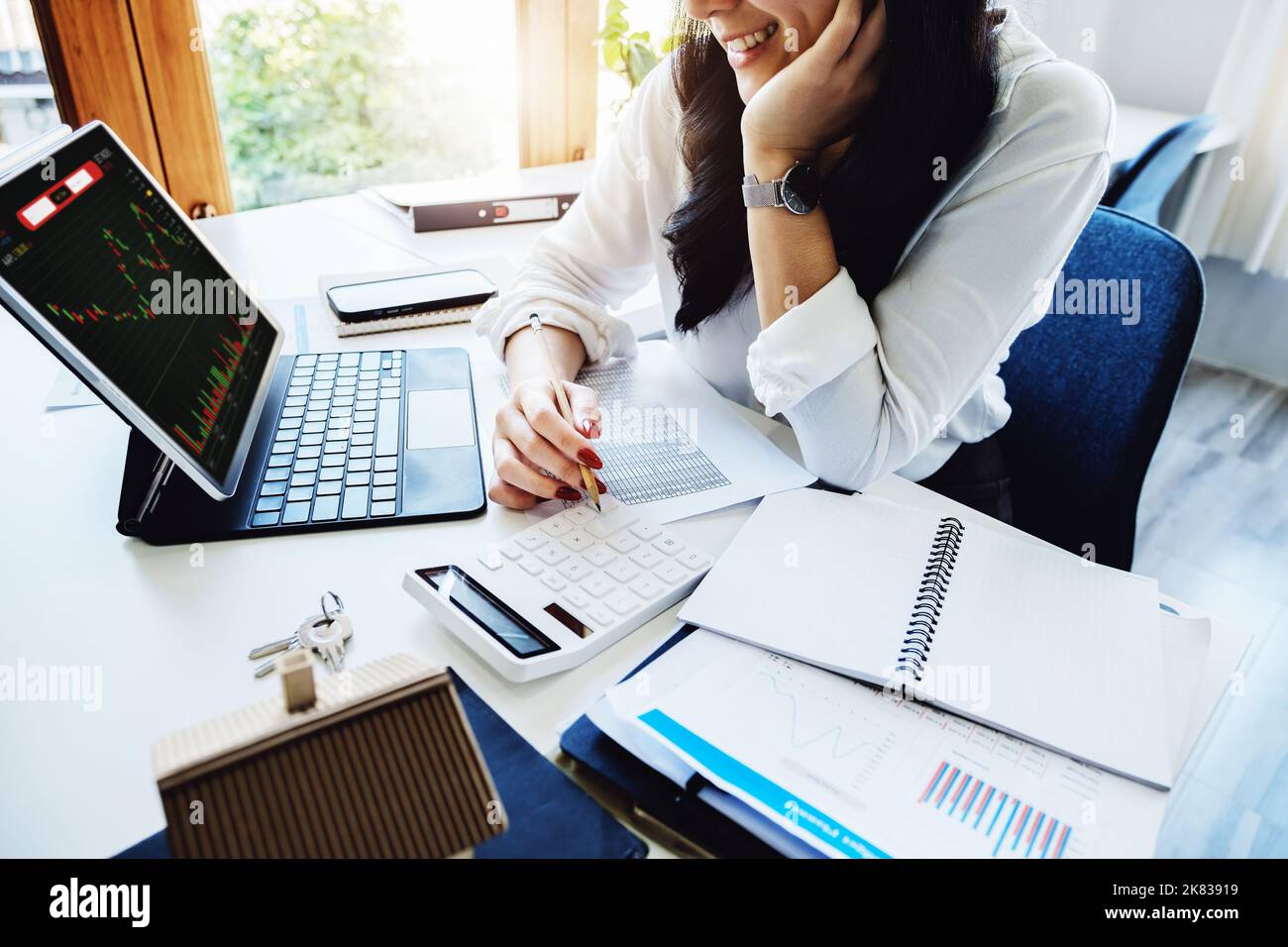 Azioni, bilancio e investimenti , Una donna asiatica sorridente con gioia tiene una penna e utilizza un calcolatore di ritorno di borsa per la sua azienda. Foto Stock