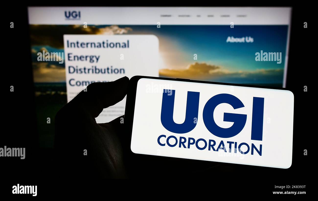 Persona che tiene in mano uno smartphone con il logo della società americana UGI Corporation sullo schermo di fronte al sito Web. Messa a fuoco sul display del telefono. Foto Stock