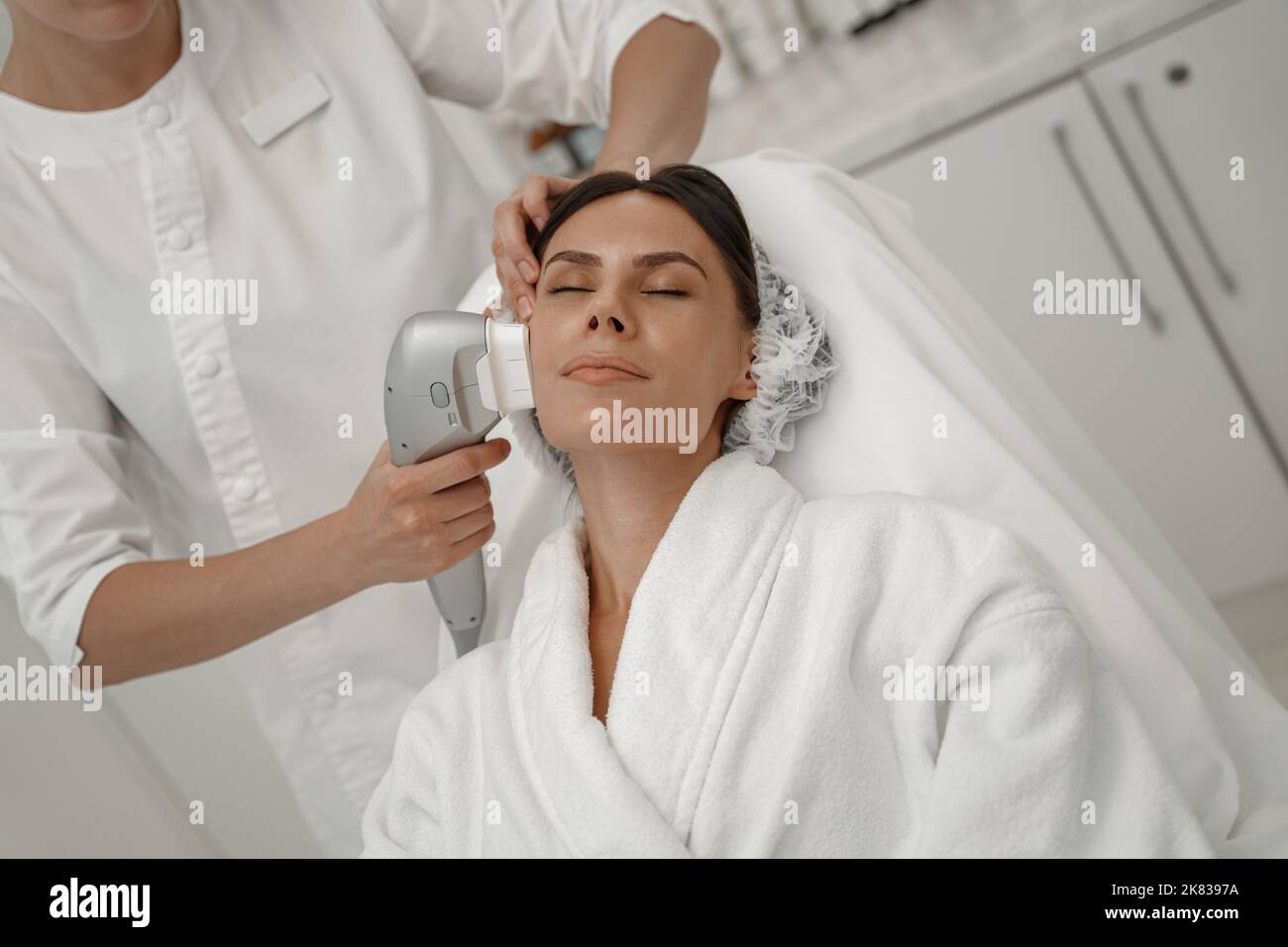 Il cosmetologo professionista sta facendo il trattamento di ringiovanimento della pelle di cavitazione. Sollevamento onde radio Foto Stock