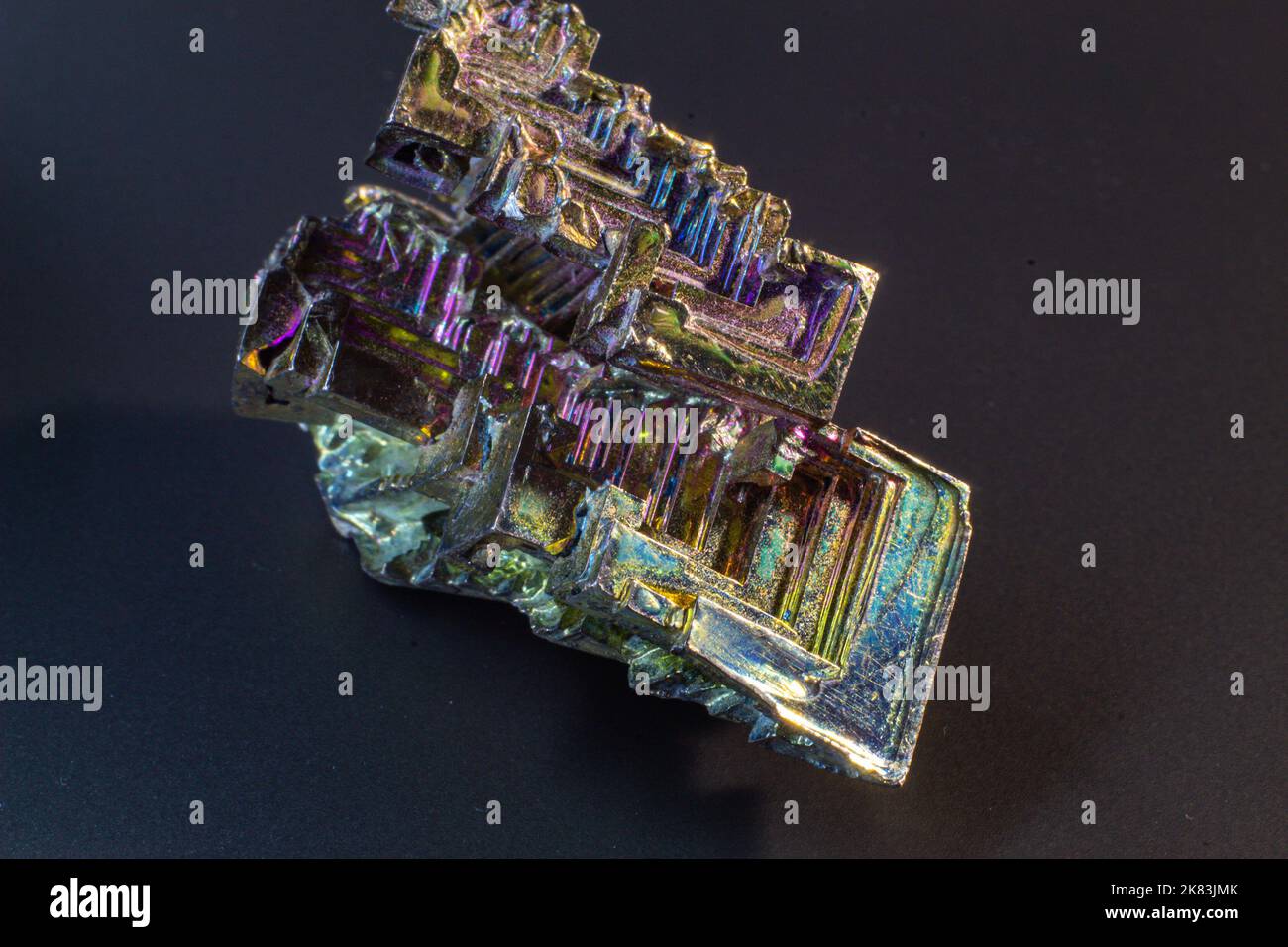 Bismuto bi primo piano su superficie nera.interessante colore e forma cristallo. Cristallo metallico Foto Stock
