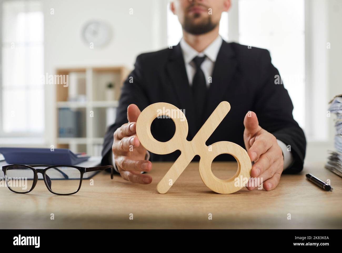 Primo piano del segno di percentuale sulla scrivania dell'ufficio dell'uomo d'affari come simbolo del tasso di interesse Foto Stock