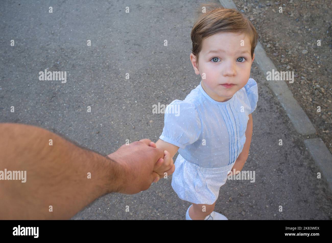 il ragazzo di 3 anni tiene la mano del padre per attraversare la strada. Punto di vista Foto Stock