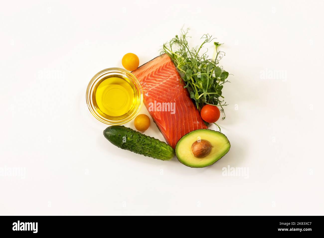 Ingredienti di cibo sano. Pesce, germogli di micro piselli verdi, olio d'oliva, cetriolo, pomodoro, avocado. Ketogenic basso concetto di dieta dei carbs. Foto Stock