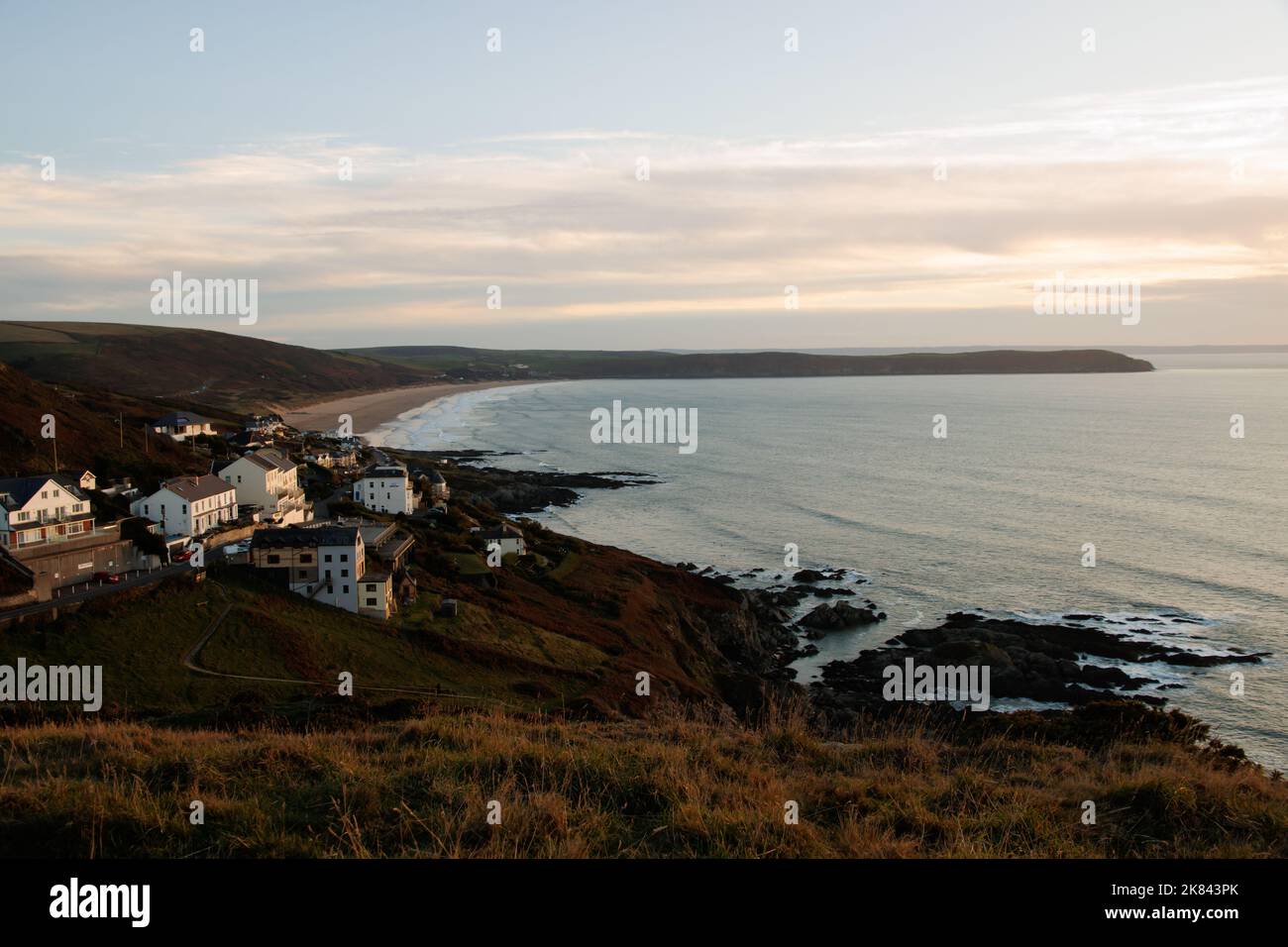 North Devon Seacoast al tramonto. Ampia vista sulla costa di Woolacombe, Inghilterra, con scogliere, rocce e onde Foto Stock