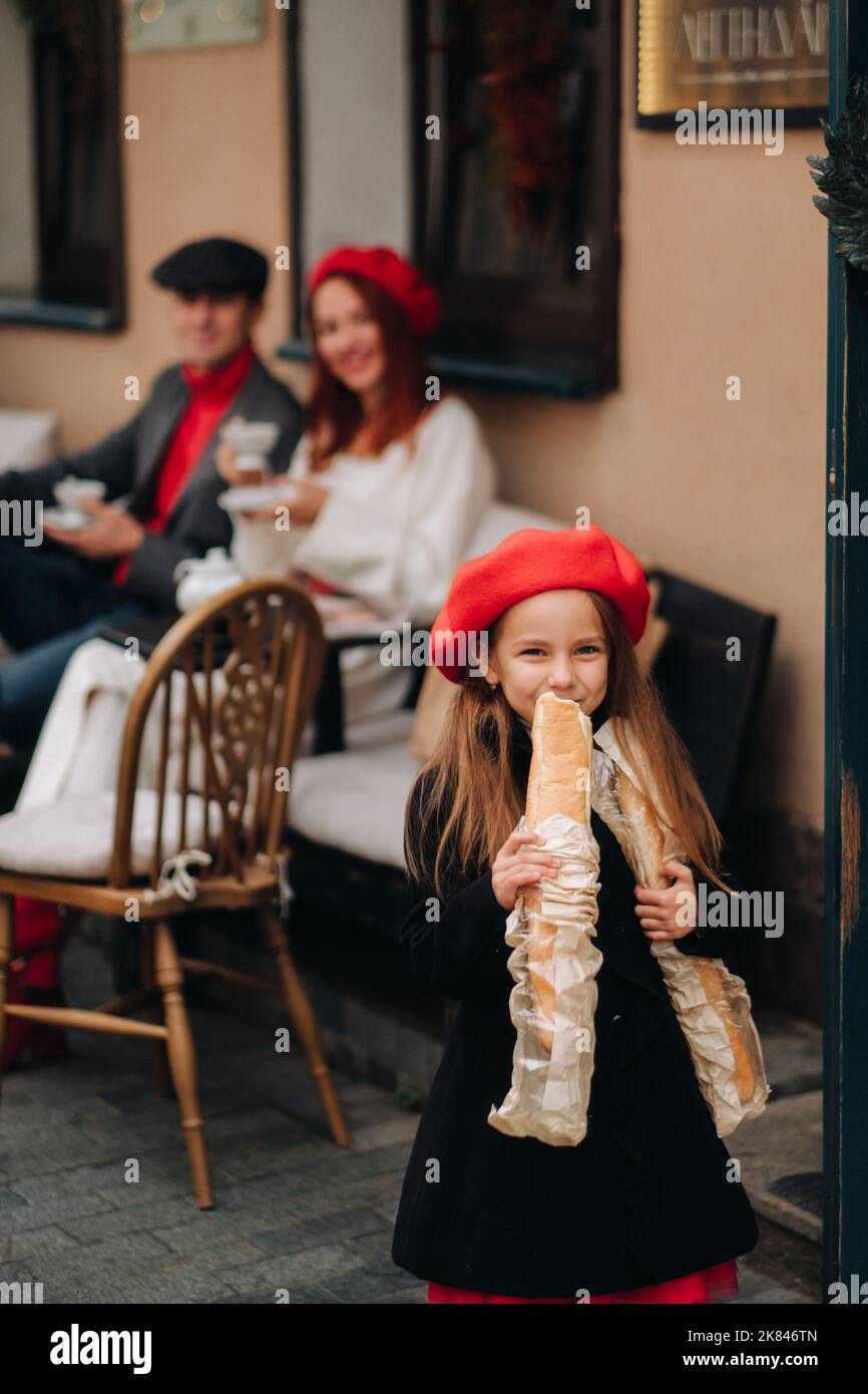 Una ragazza alla moda con baguette si trova vicino al negozio sullo sfondo dei suoi genitori Foto Stock