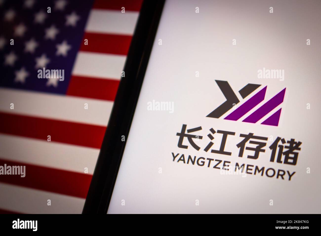 Logo Yangtze Memory Technologies Corp su iPhone sulla bandiera degli Stati Uniti di umore oscuro. YMTC è un produttore cinese di dispositivi integrati semiconduttori Foto Stock