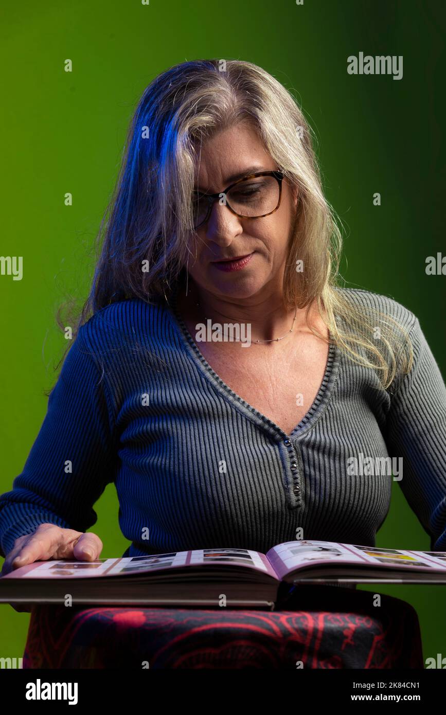 Ritratto di una donna che guarda il libro su sfondo verde. Concetto di studio. Donna tranquilla. Foto Stock