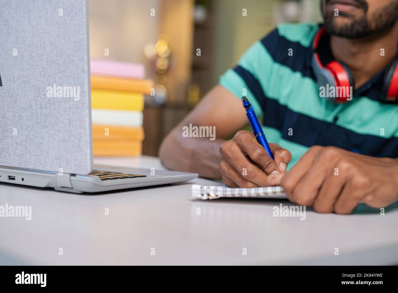 Immagine ravvicinata dell'uomo che utilizza il laptop per scrivere appunti durante la lezione online o il tutorial a casa - concetti di e-learning, istruzione a distanza e Internet. Foto Stock