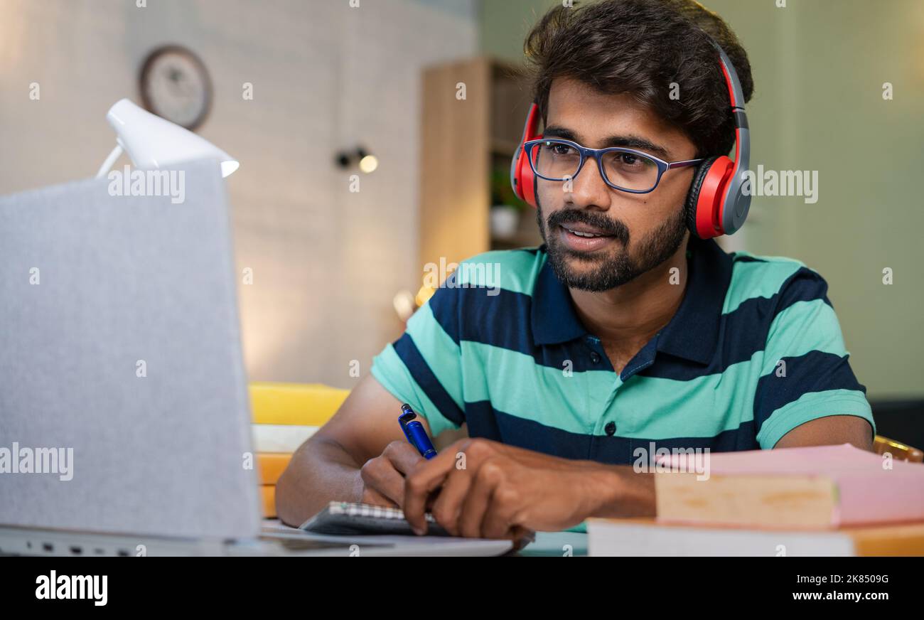 studnet scrivere appunti vedendo il portatile a casa - concetto di educazione online, apprendimento a distanza e intelligenza. Foto Stock