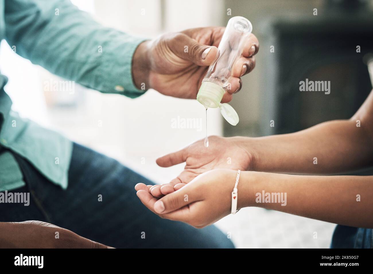 Insegnate ai vostri bambini l'igiene. Due persone non riconoscibili che usano l'igienizzatore per le mani a casa. Foto Stock