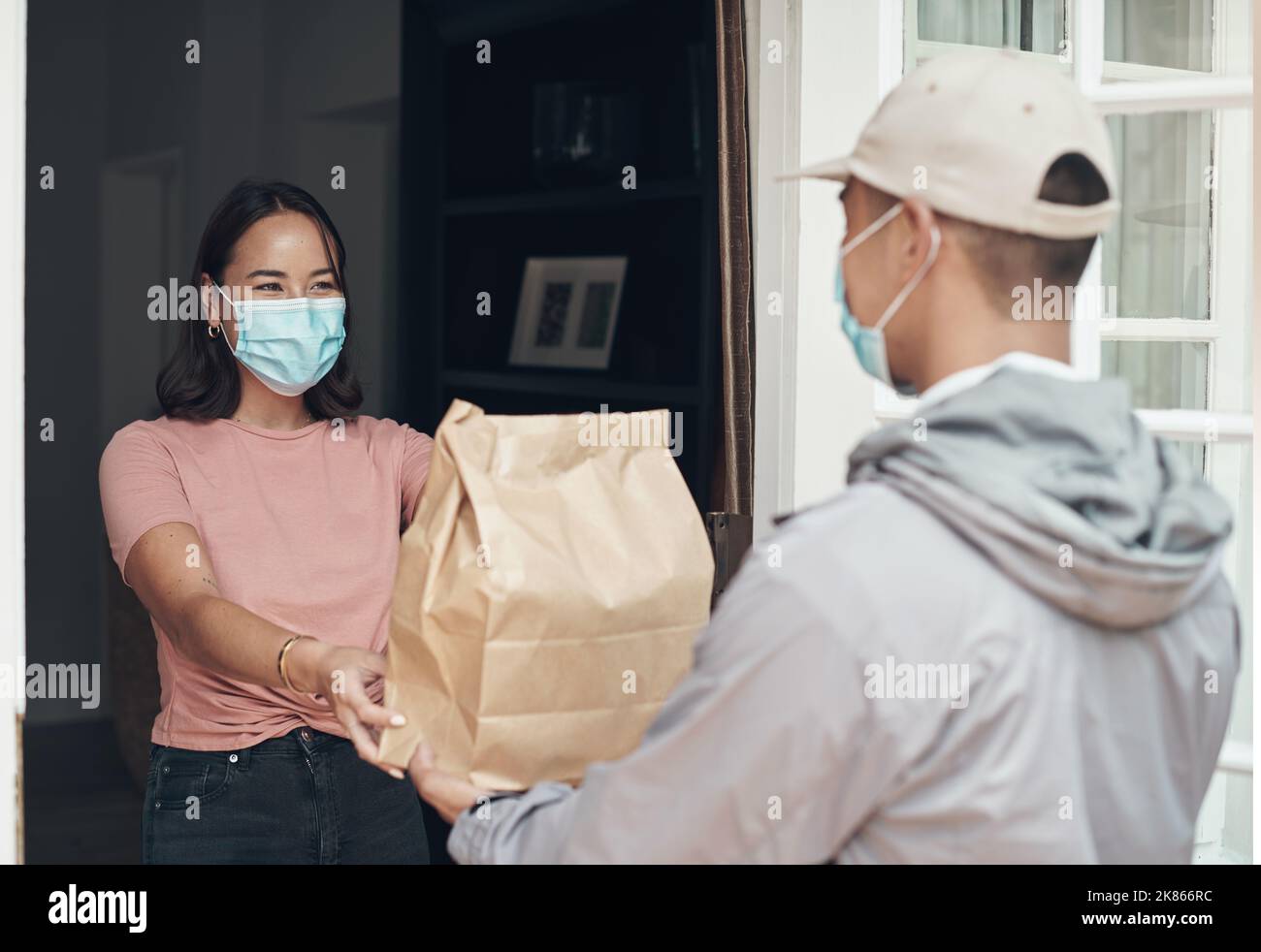 Il vostro ordine è la mia consegna. Un giovane che consegna un pacco a un cliente a casa. Foto Stock