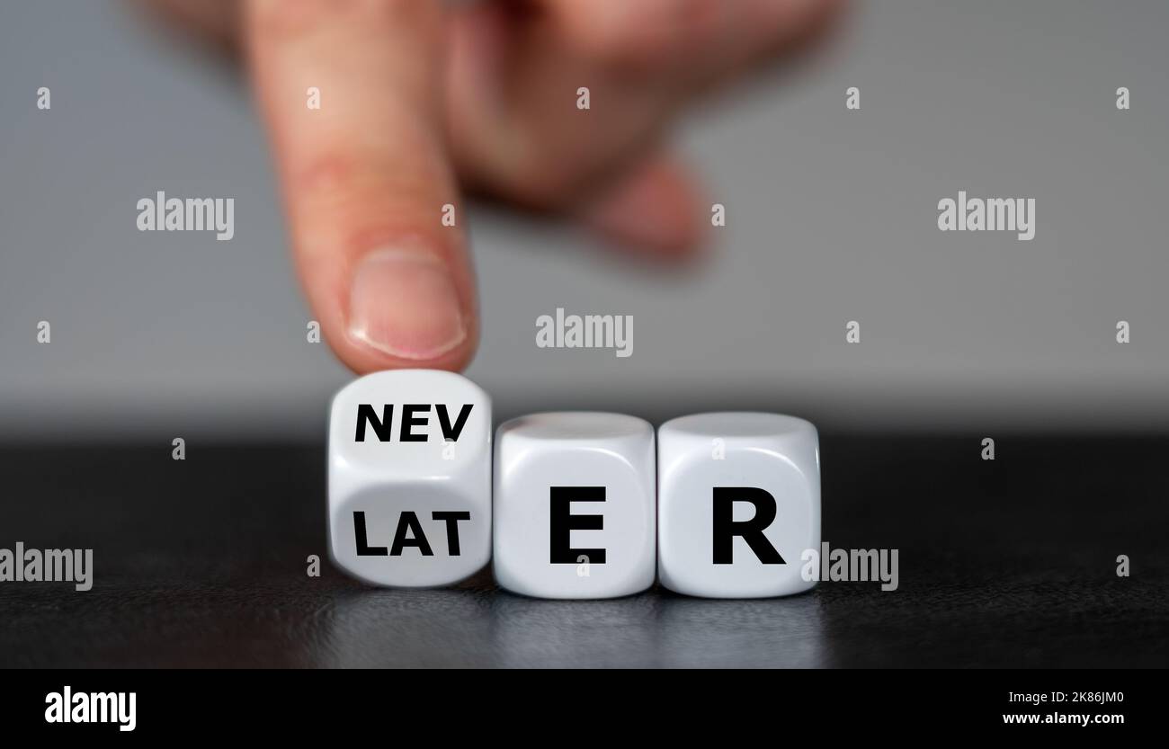 Simbolo per lo slogan "a volte più tardi diventa mai". La mano gira i dadi e cambia la parola più tardi in mai. Foto Stock