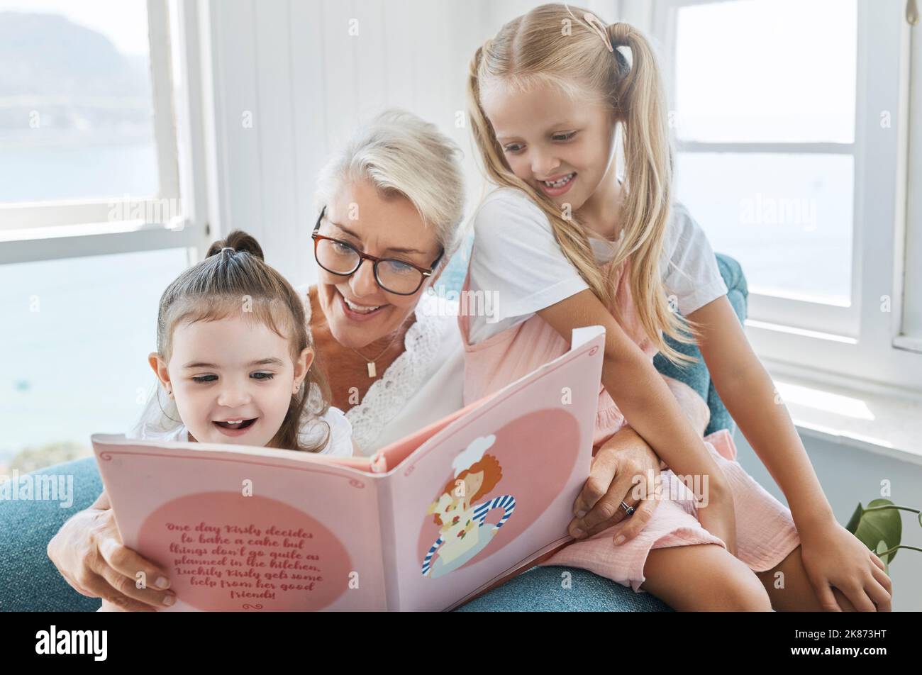 Libro, lettura e nonna con bambini per l'apprendimento, lo sviluppo della lingua e l'educazione all'inglese nel divano del soggiorno. Famiglia anziana, donna anziana Foto Stock