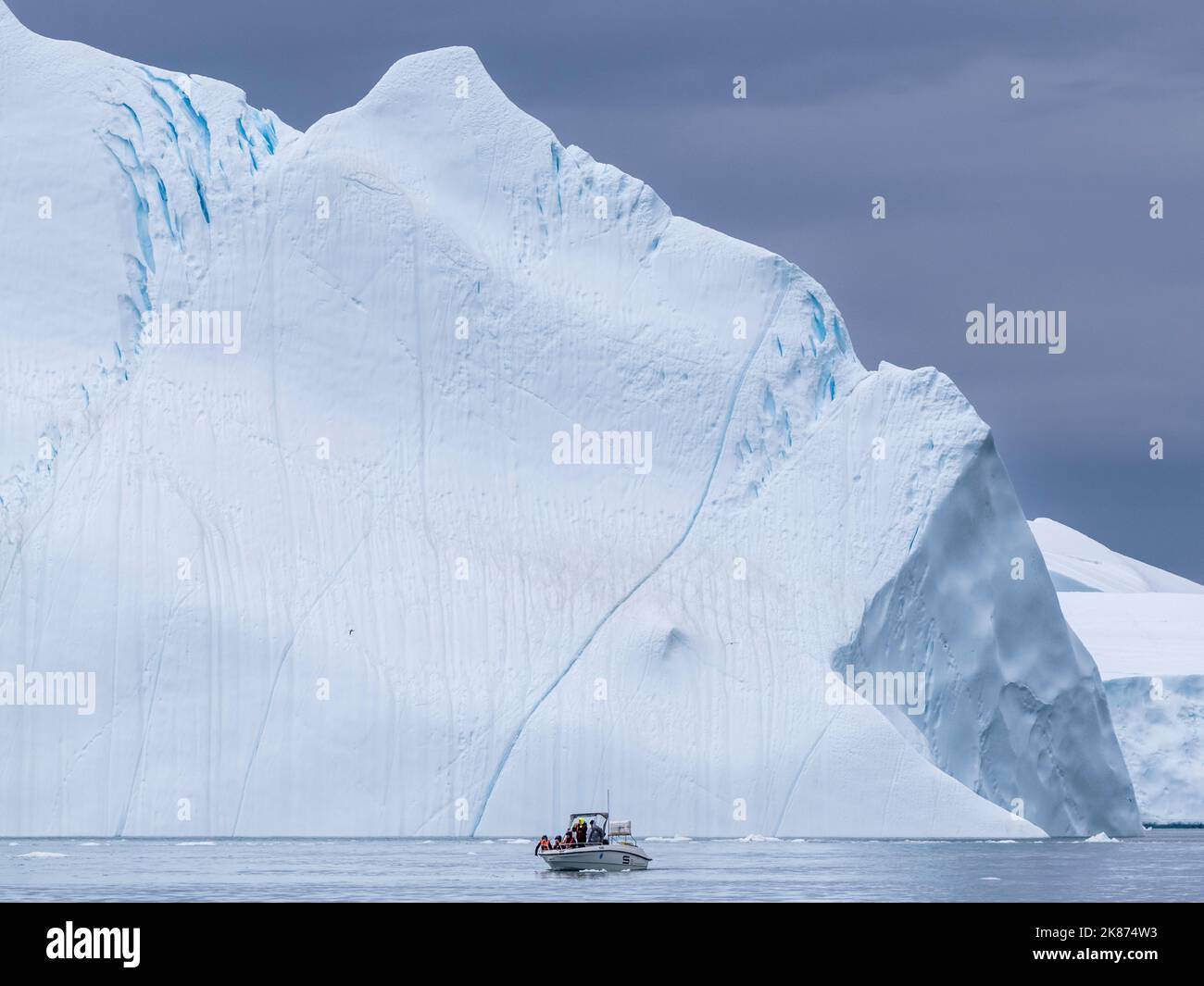 I turisti che partecipano a un tour sul ghiaccio in una piccola barca che guarda gli iceberg dall'Icefjord di Ilulissat, appena fuori Ilulissat, Groenlandia, Danimarca, regioni polari Foto Stock
