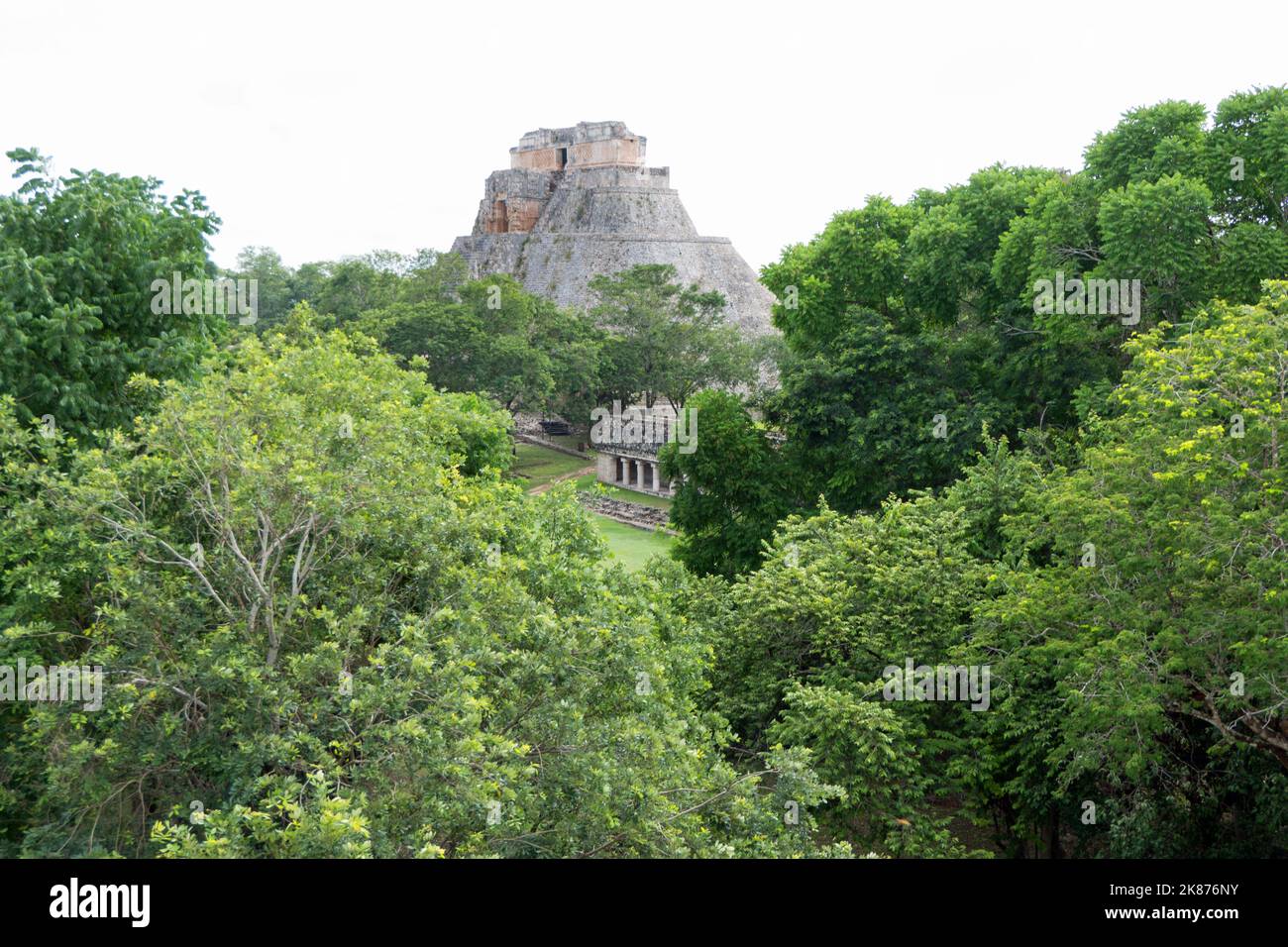 Vista del sito archeologico Maya di Uxmal a Yucatan, Messico. Rovine Maya con piramide del mago e antichi edifici per i turisti e trave Foto Stock