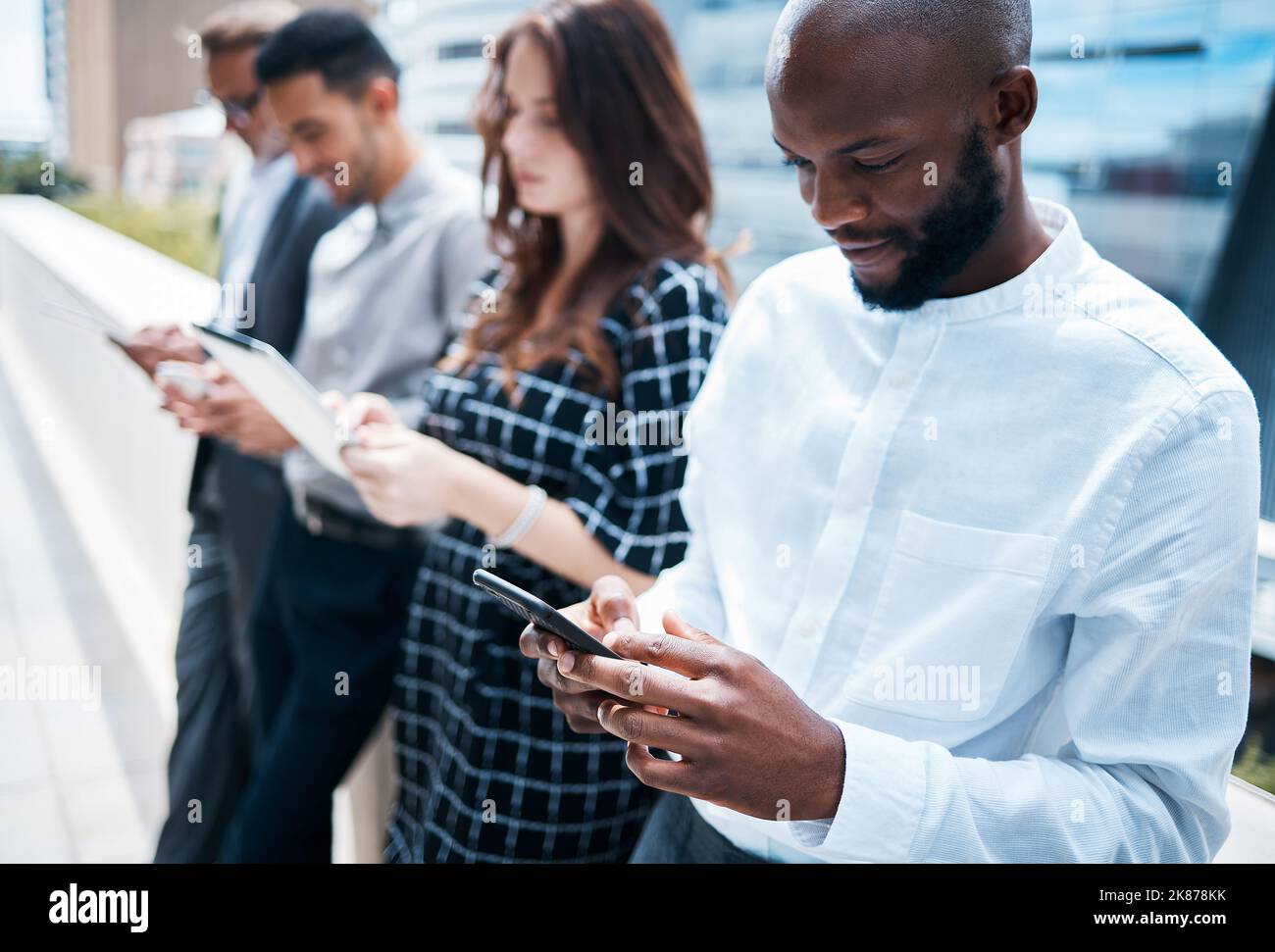 I dispositivi wireless sono così comodi per gli uomini d'affari moderni. Gli uomini d'affari utilizzano vari dispositivi su un background urbano. Foto Stock